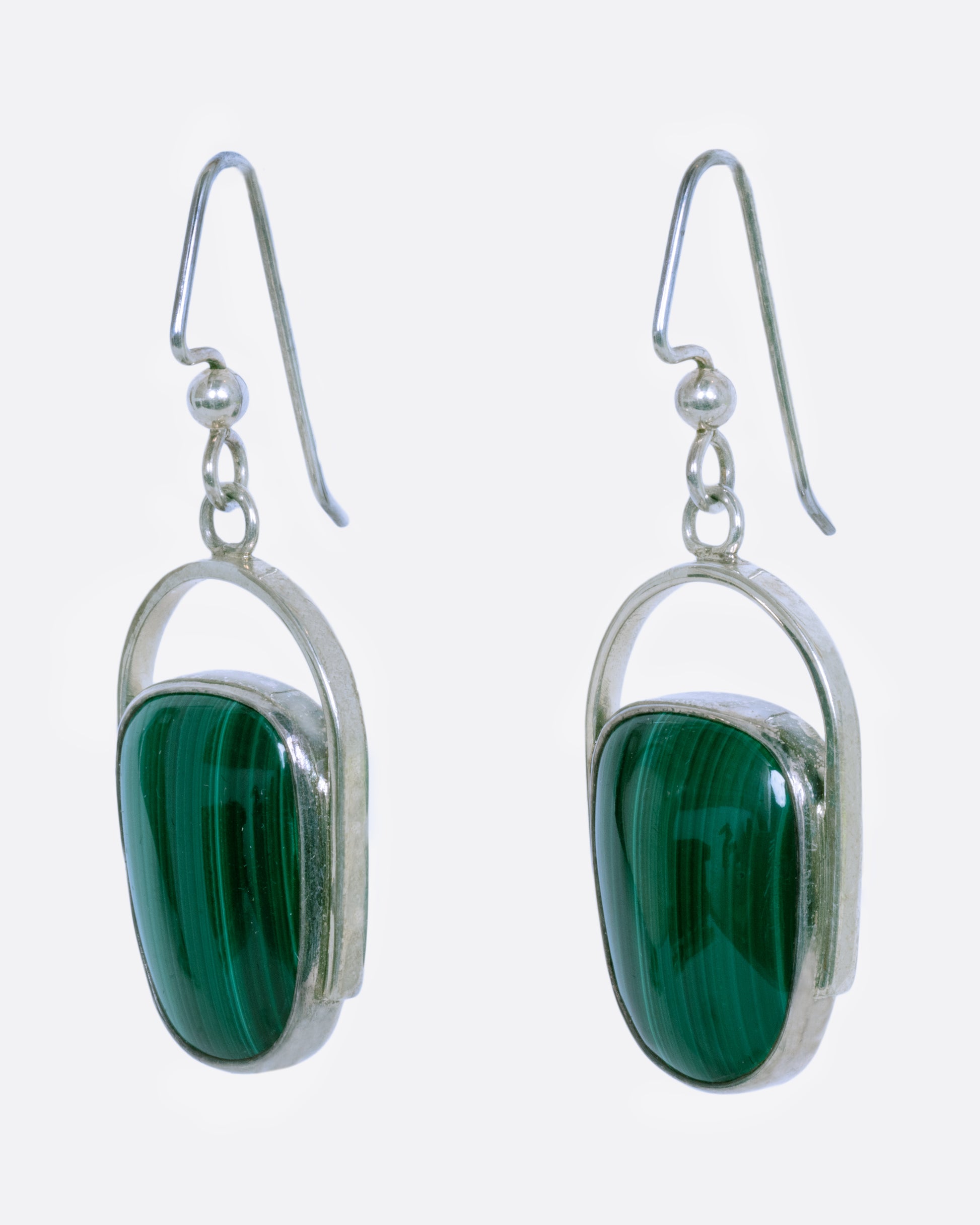 Sterling silver curved drop earrings with malachite. View from the side.