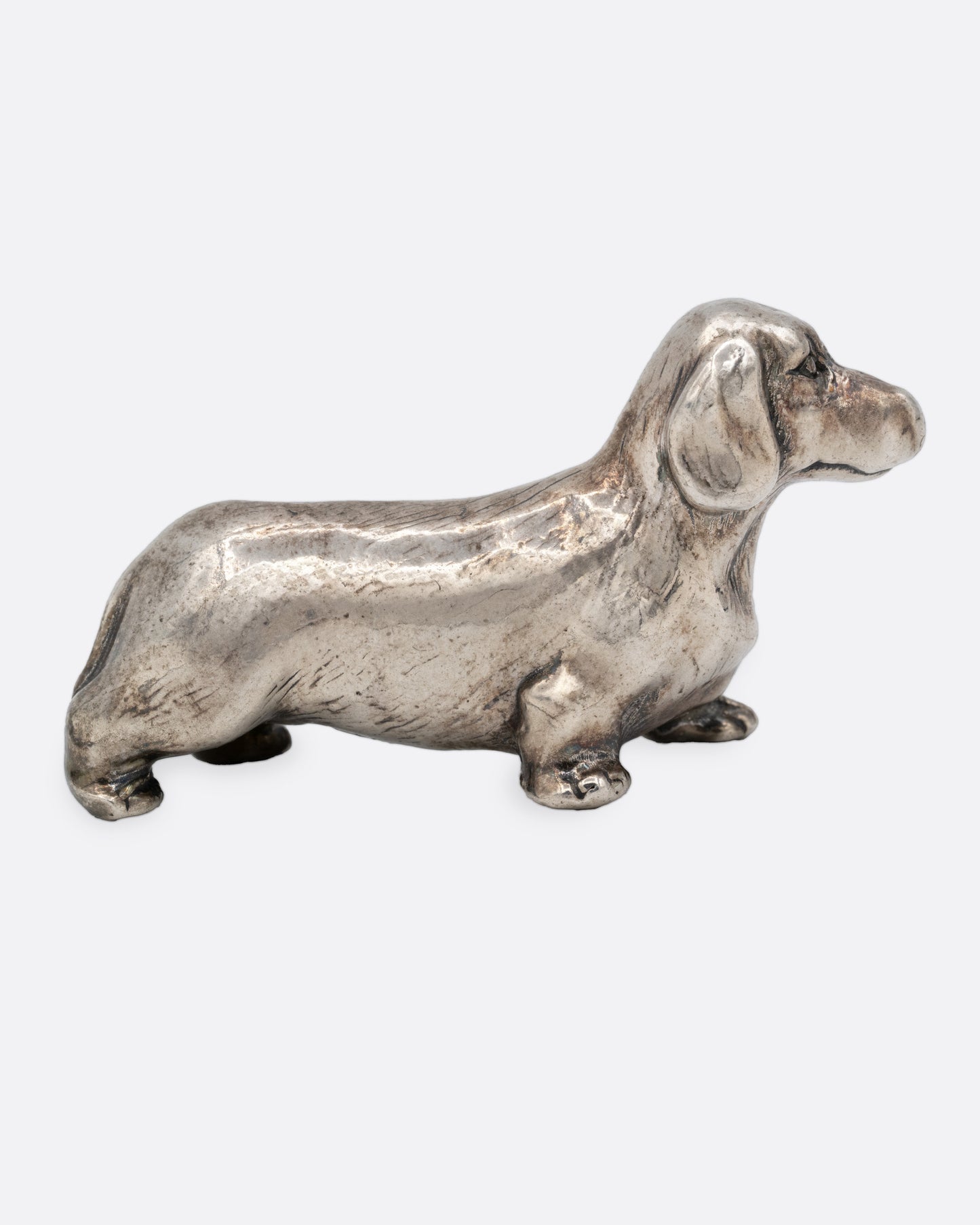 A silver dachshund figurine, shown from the side.