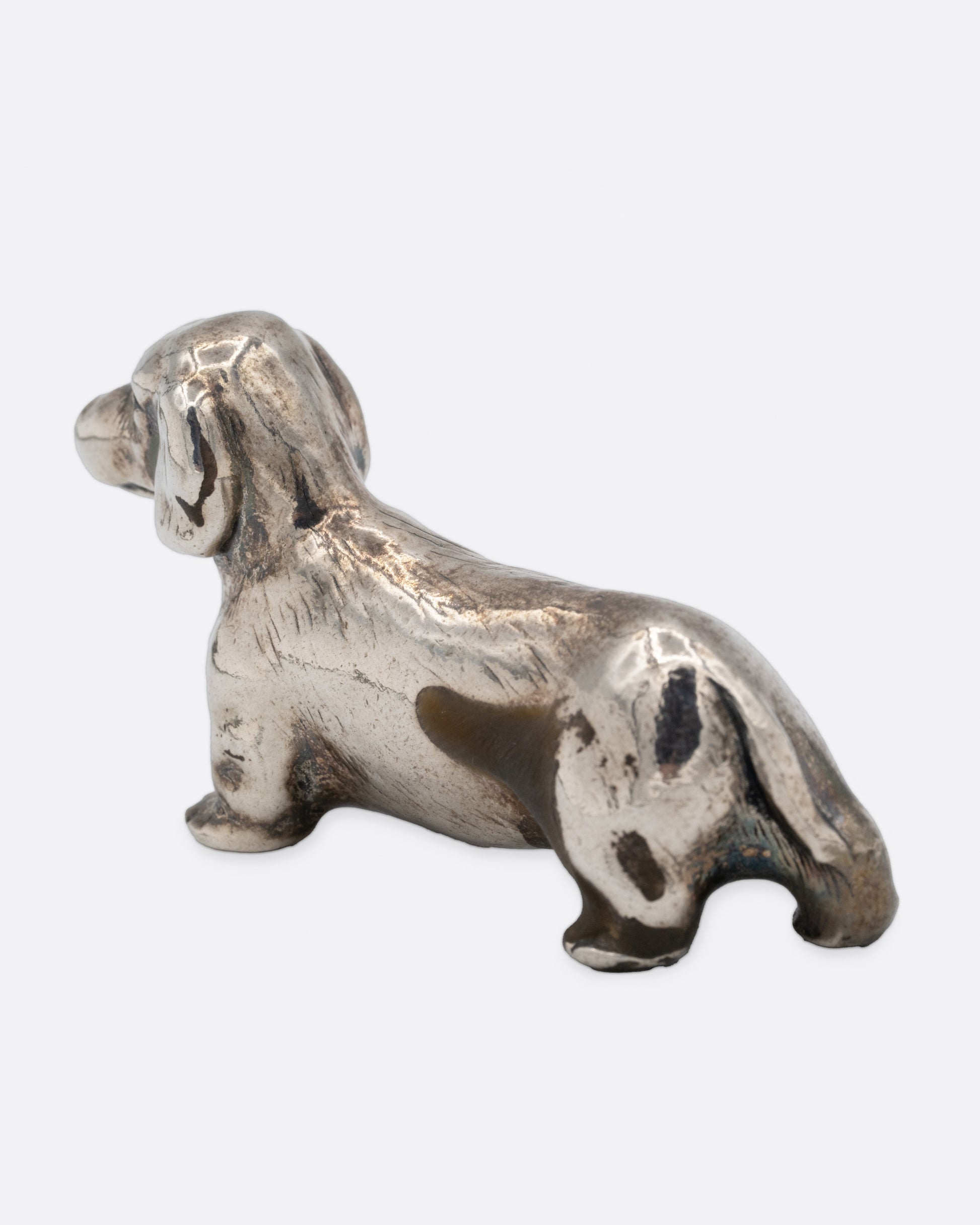 A silver dachshund figurine, shown from the back.