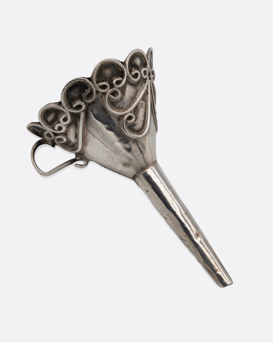 A small silver funnel with decorative scroll work at the top. Shown from the side.