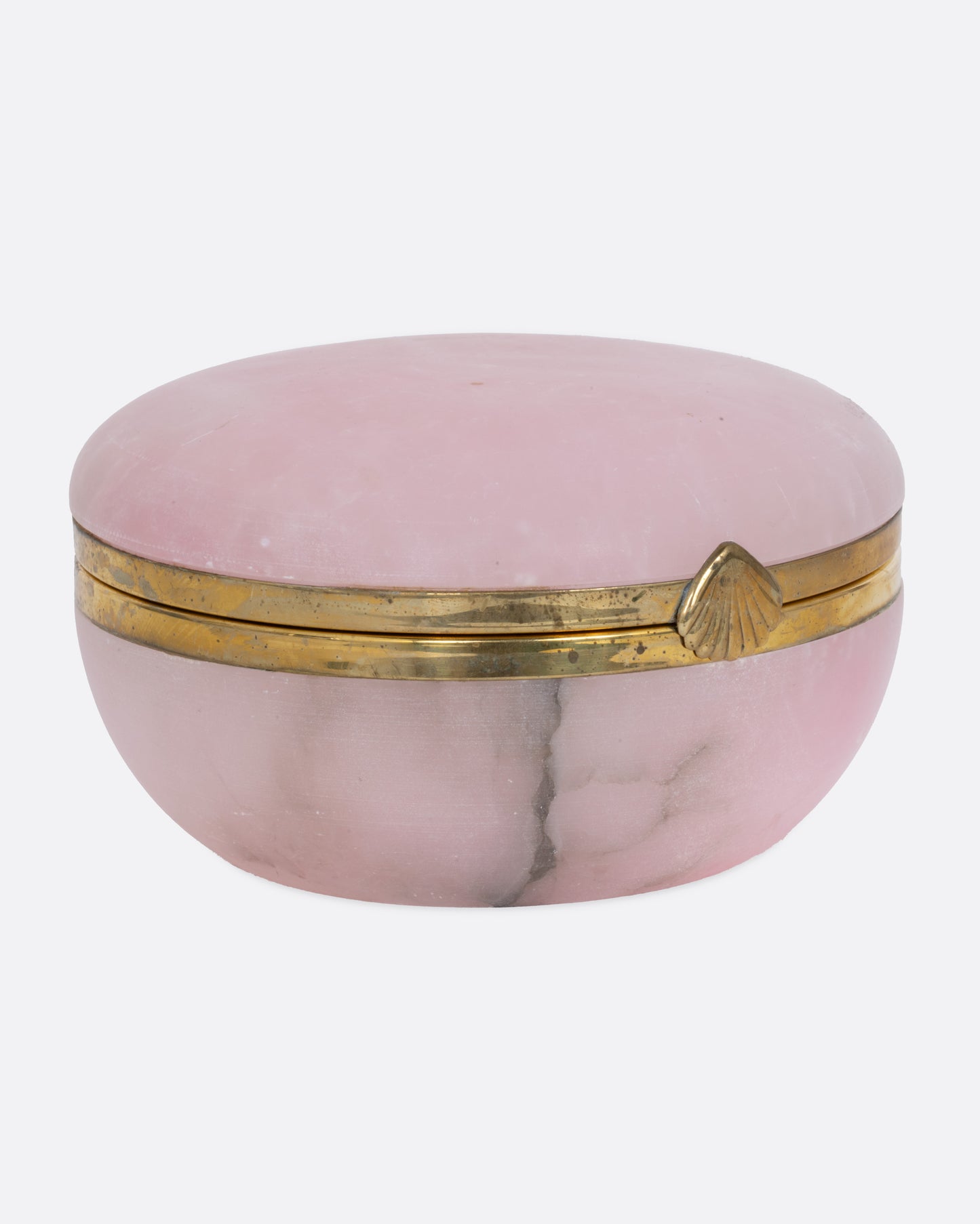 A round pink alabaster box with gold edges and a seashell shaped clasp, shown from the front.