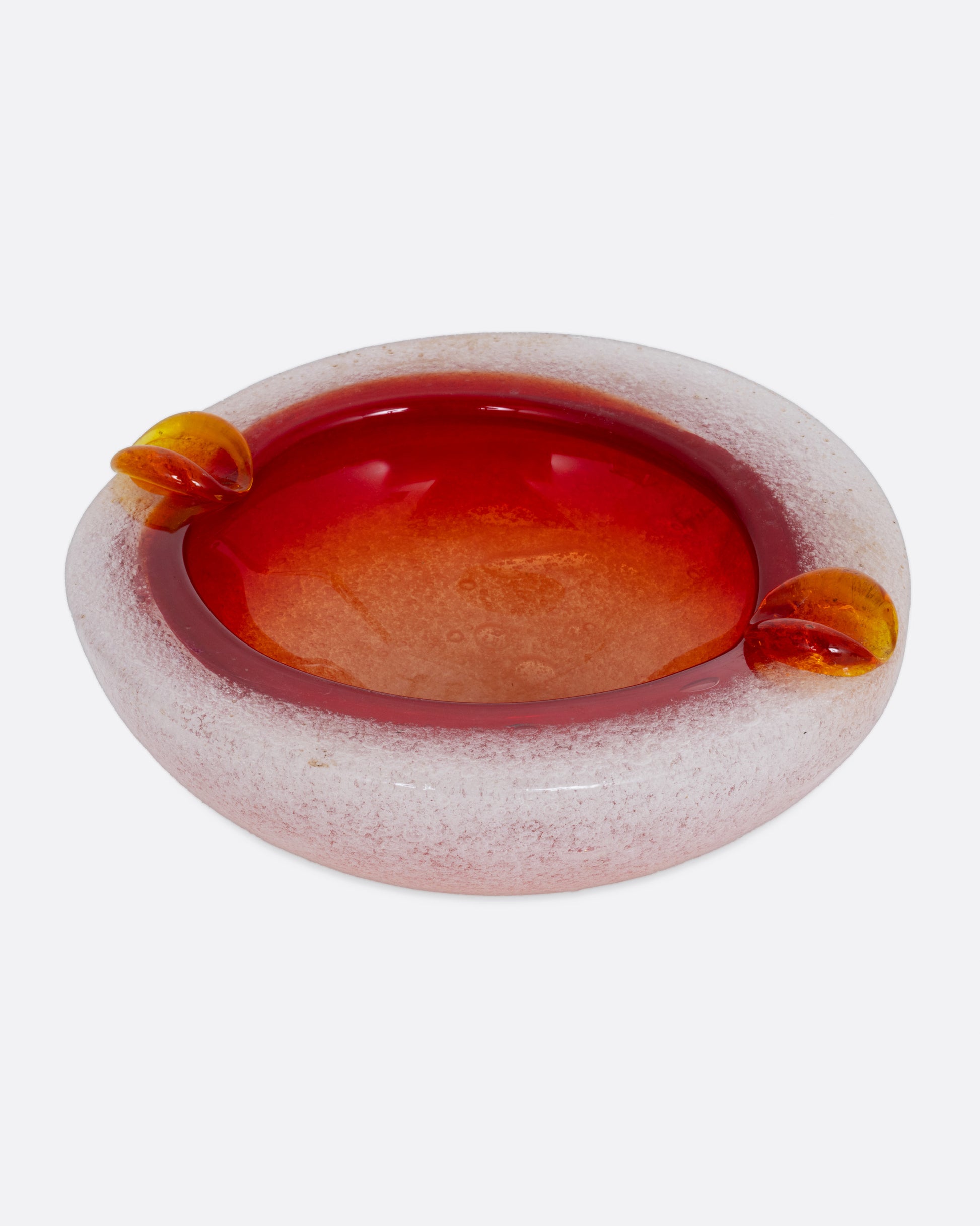 An orange and white blown glass ashtray, shown from the front.