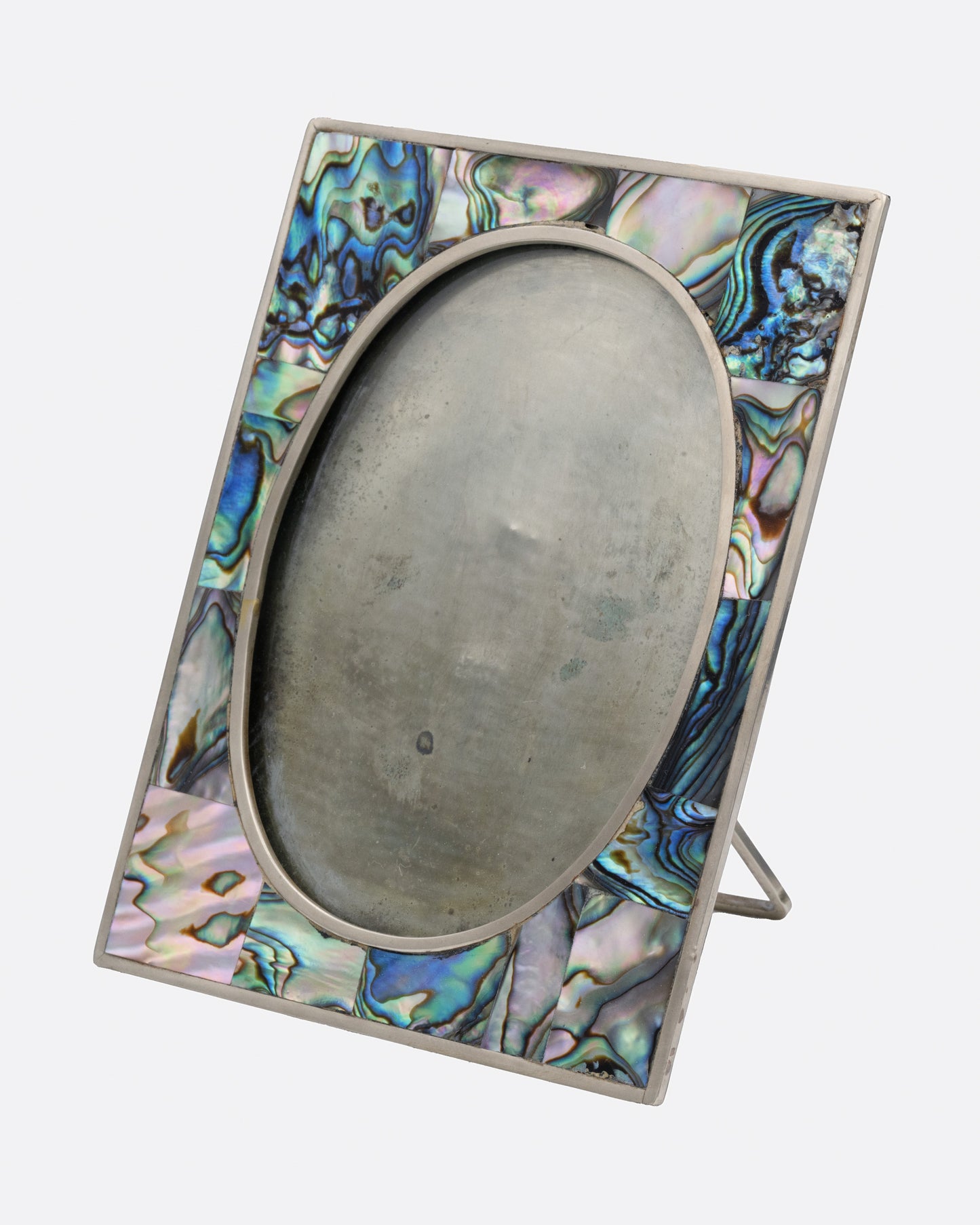A rectangular silver frame with abalone inlay and an oval center. Shown from the side.