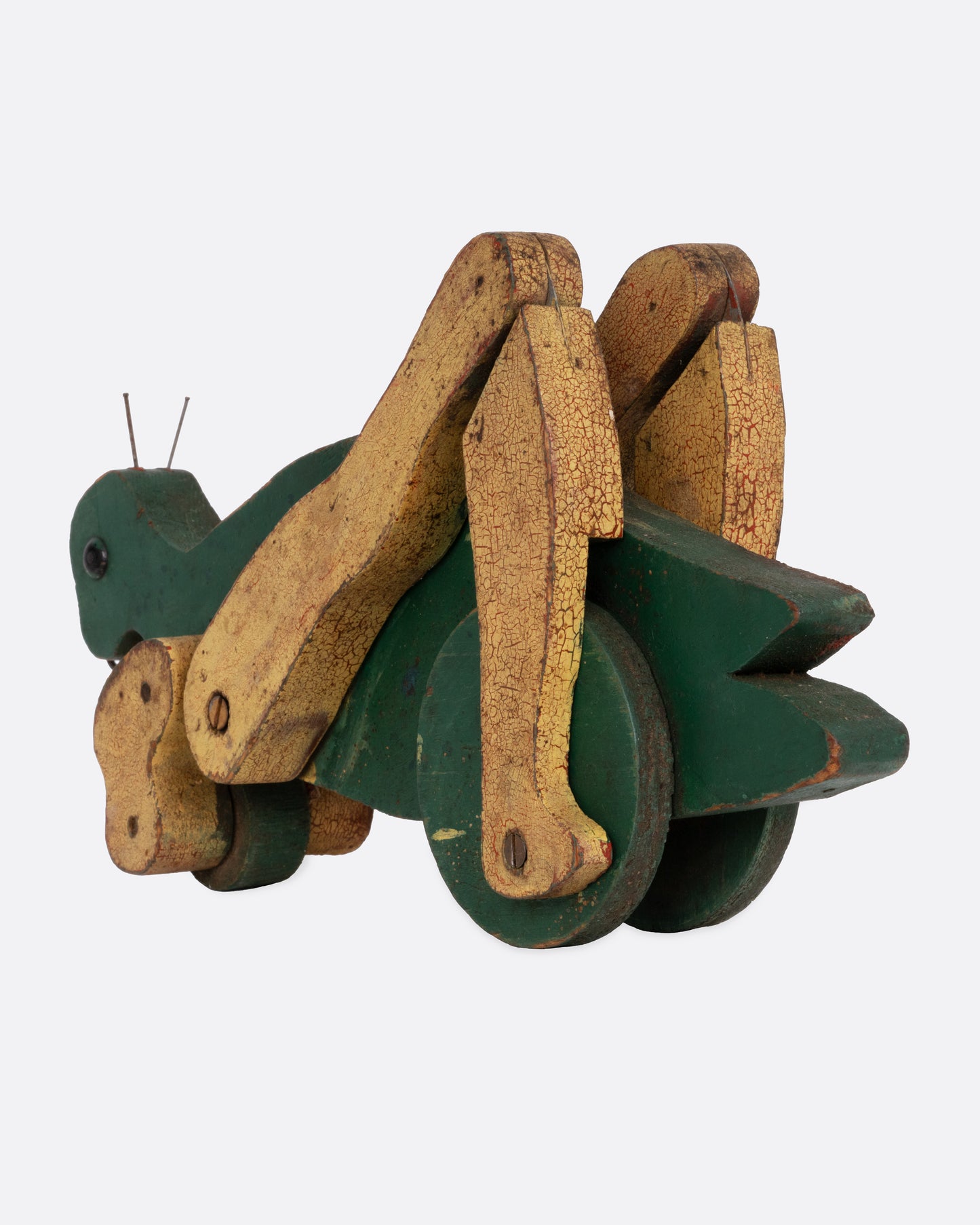 A green wooden articulated grasshopper toy, shown from the back.