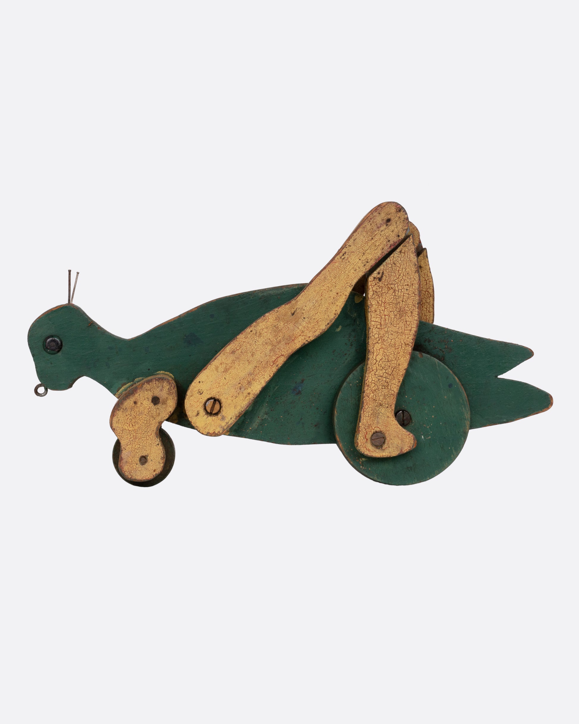 A green wooden articulated grasshopper toy, shown from the side.