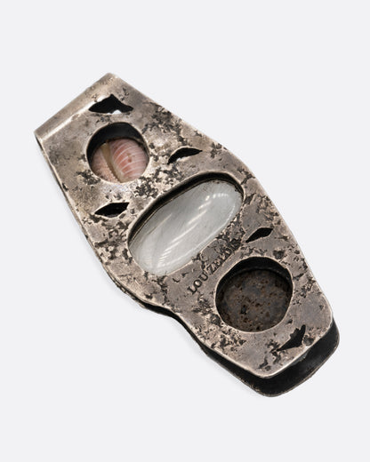 A textural silver money clip with a  pebble, quartz, and seashell set in the front, shown from the back.