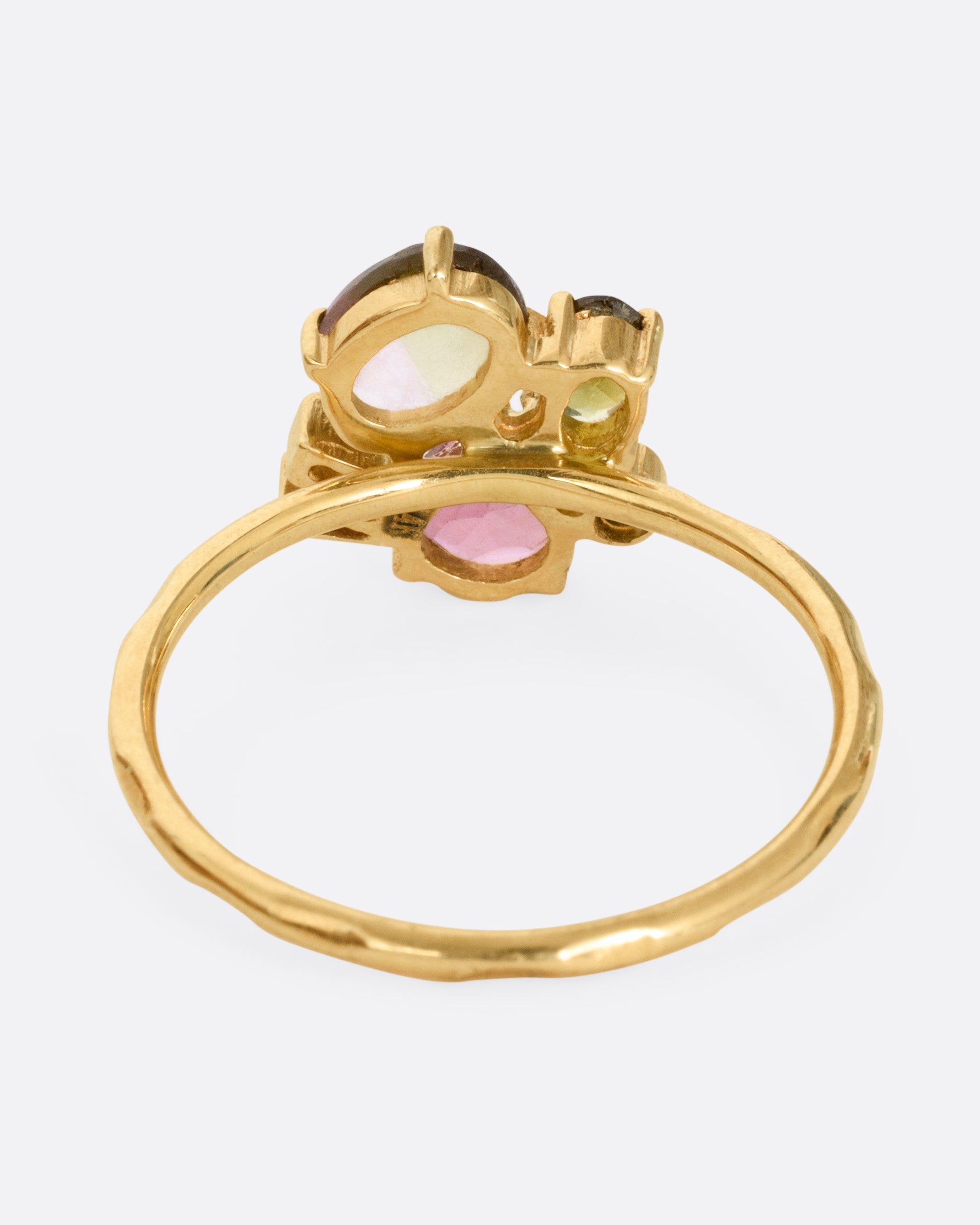 A yellow gold ring with green and pink tourmalines and three diamonds. Shown from the back.