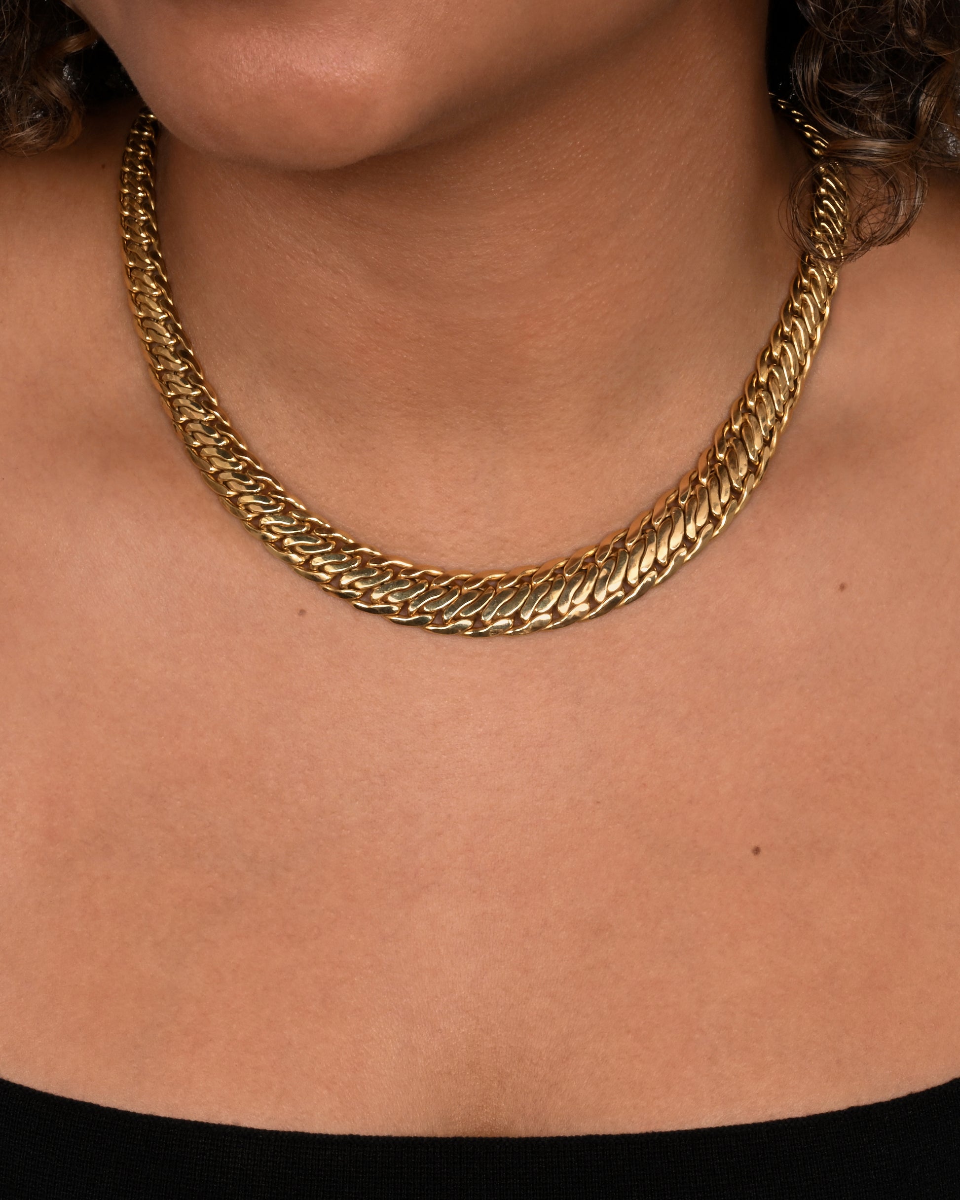 A yellow gold flat double curb chain necklace. Shown on a neck.