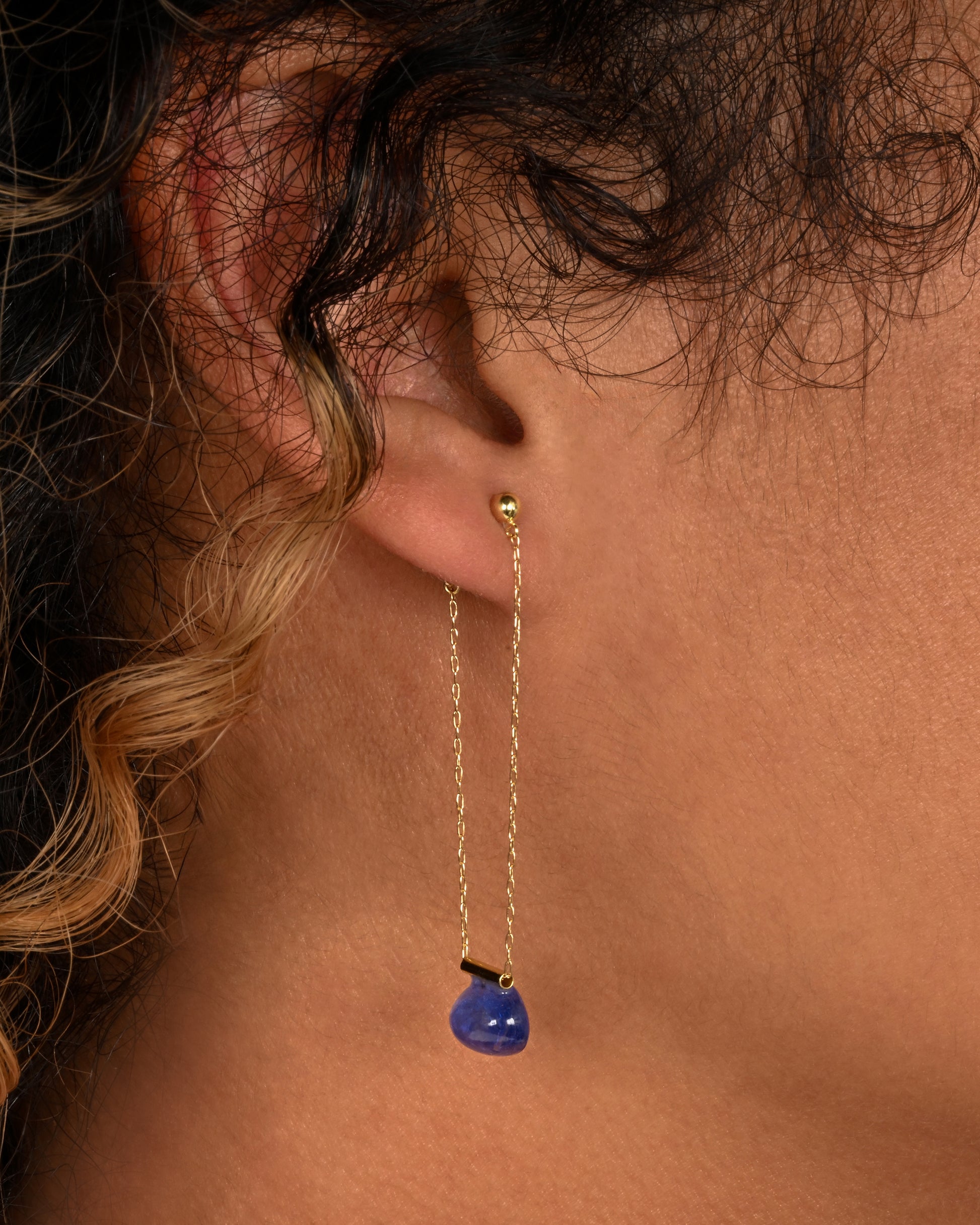 yellow gold chain earrings with tanzanite shown on an ear