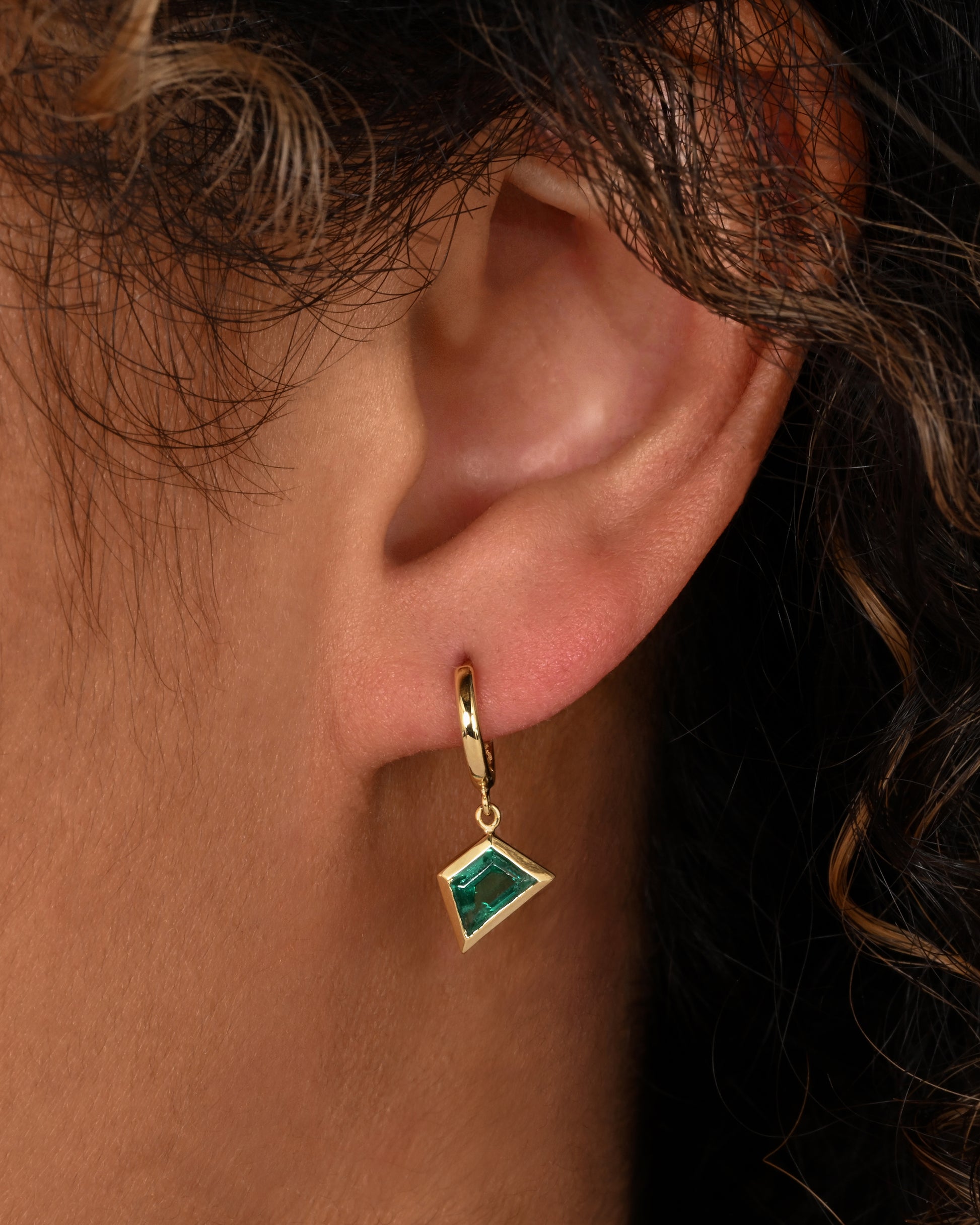 A yellow gold number "7" pendant made of mosaic multicolor sapphires and diamonds. Shown on an ear.