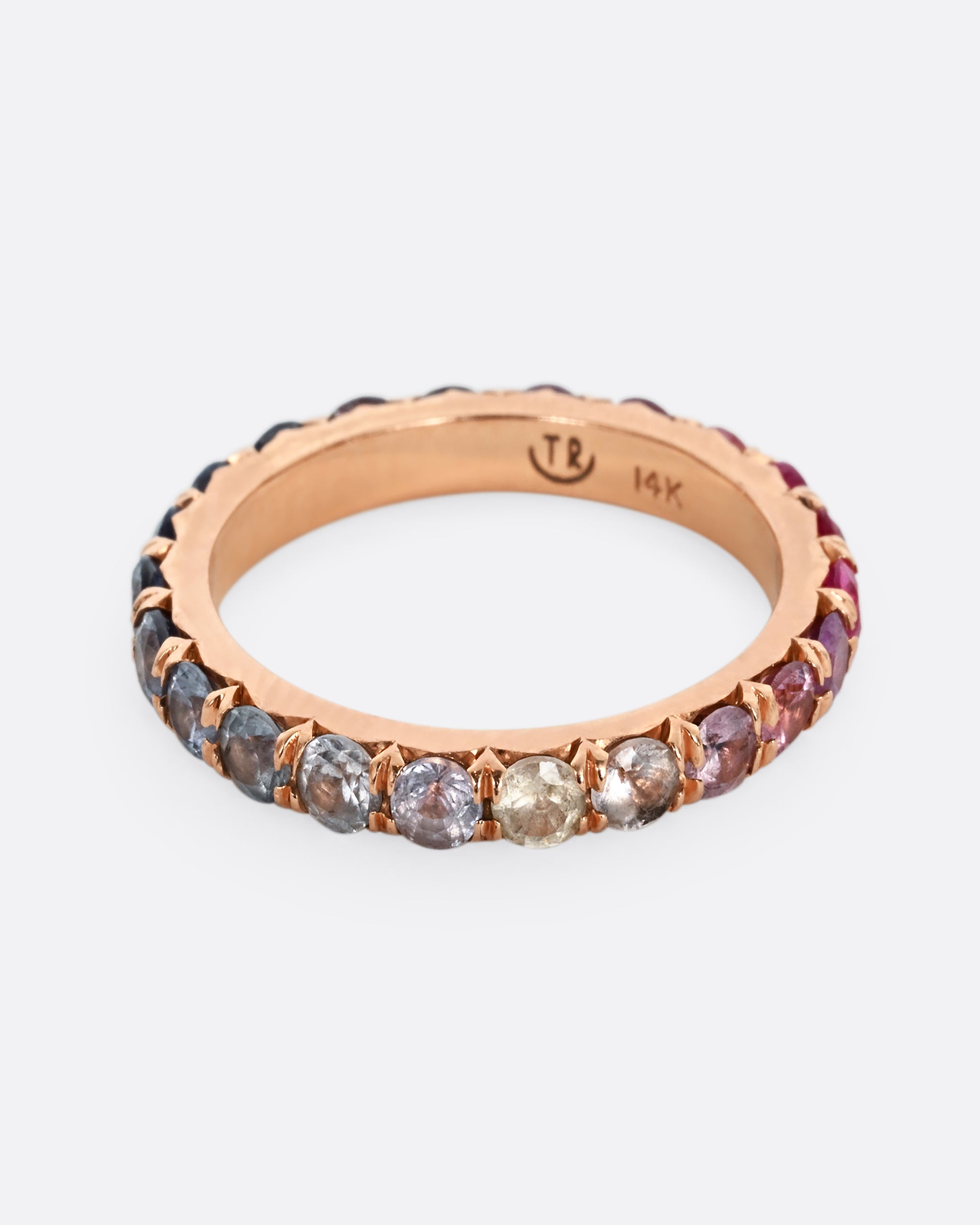 A rose gold eternity band with pink and blue cut sapphires. 