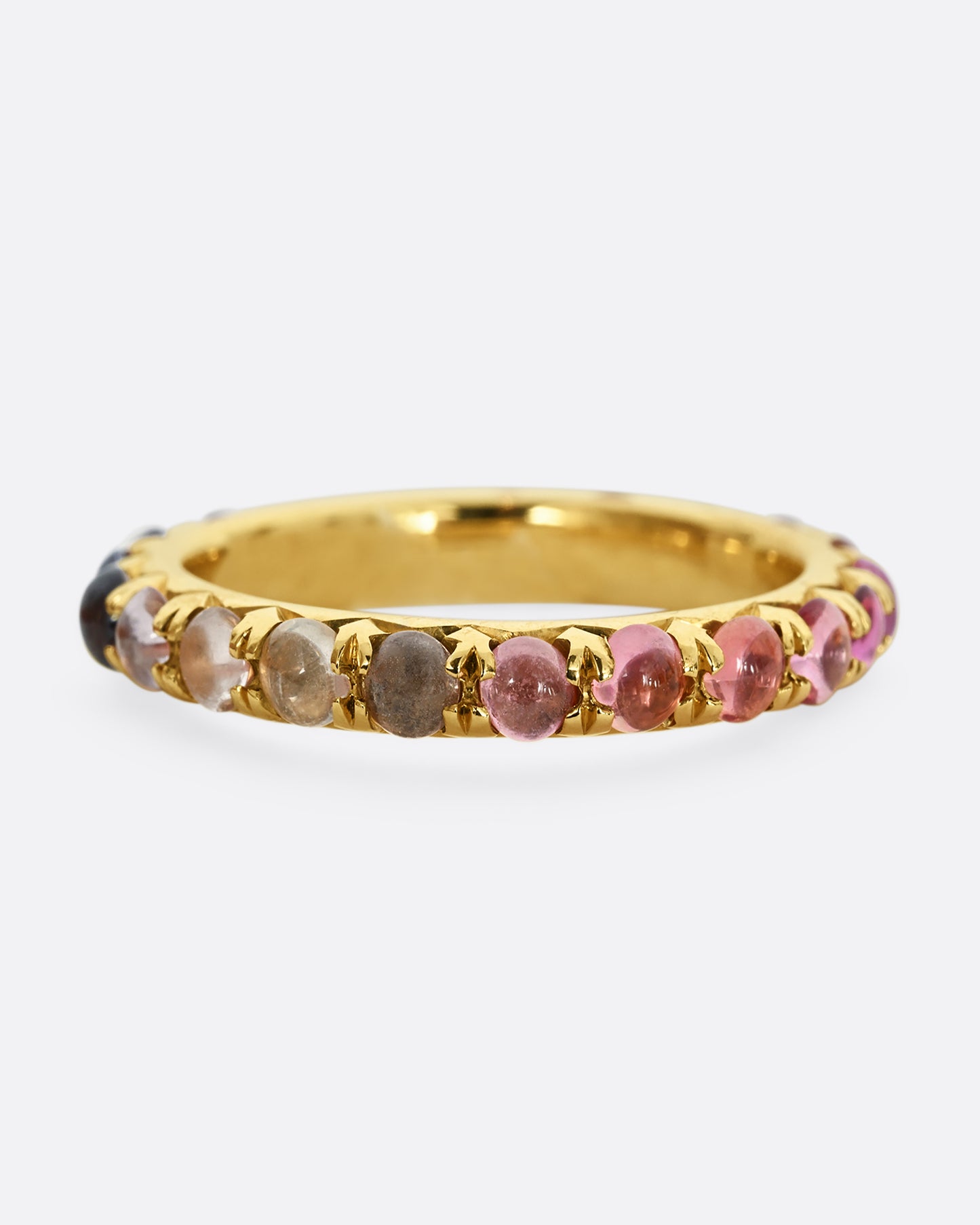 A yellow gold eternity band with pink and purple sapphire cabochons. 