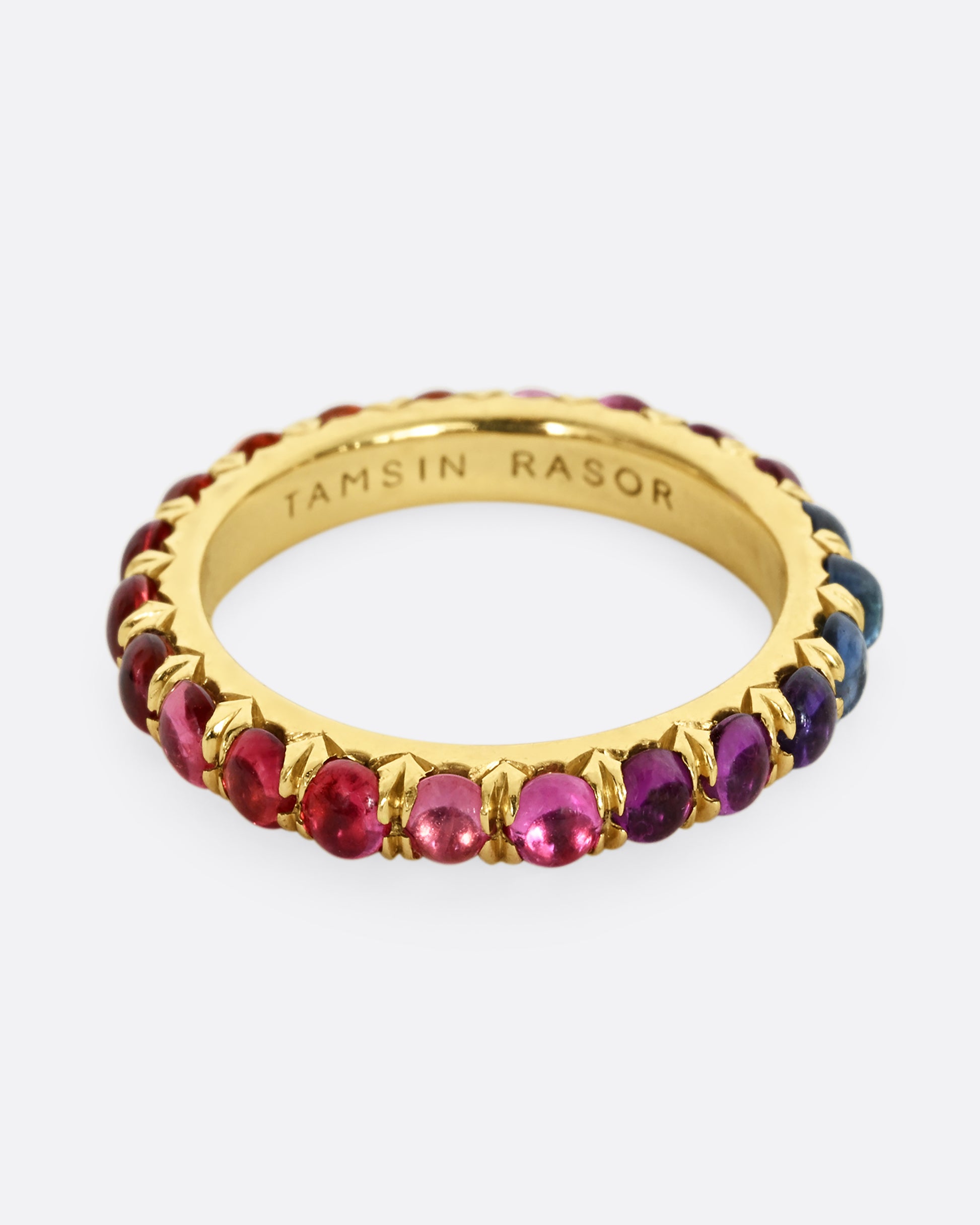 A yellow gold eternity band with rainbow sapphire cabochons.