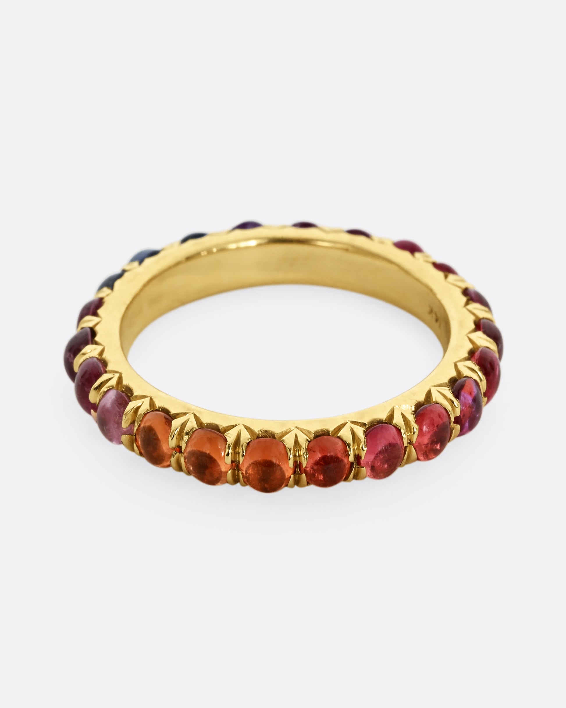 A yellow gold eternity band with rainbow sapphire cabochons.