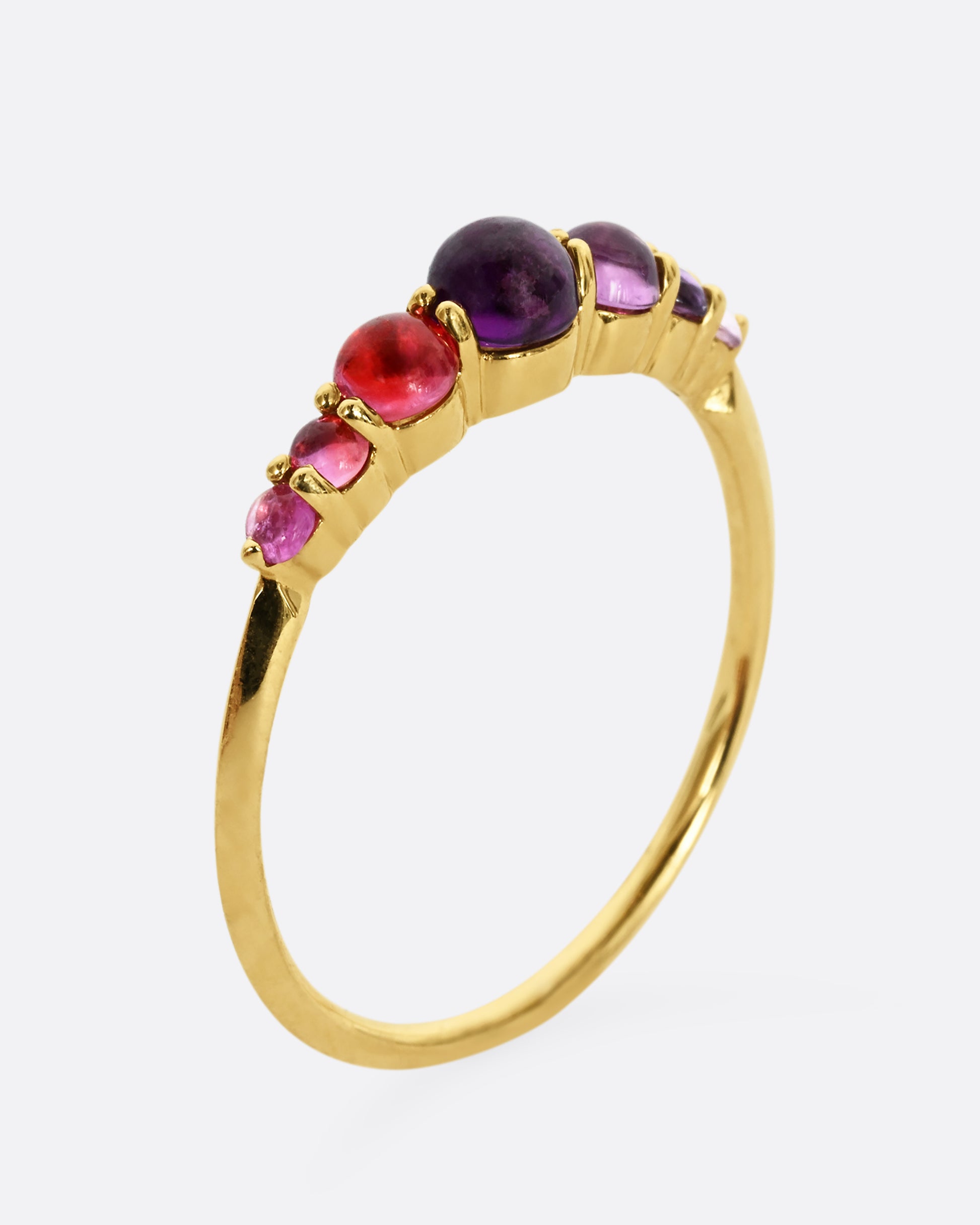 Pink and purple graduated sapphires set in 18k yellow gold. View from the side, standing up.