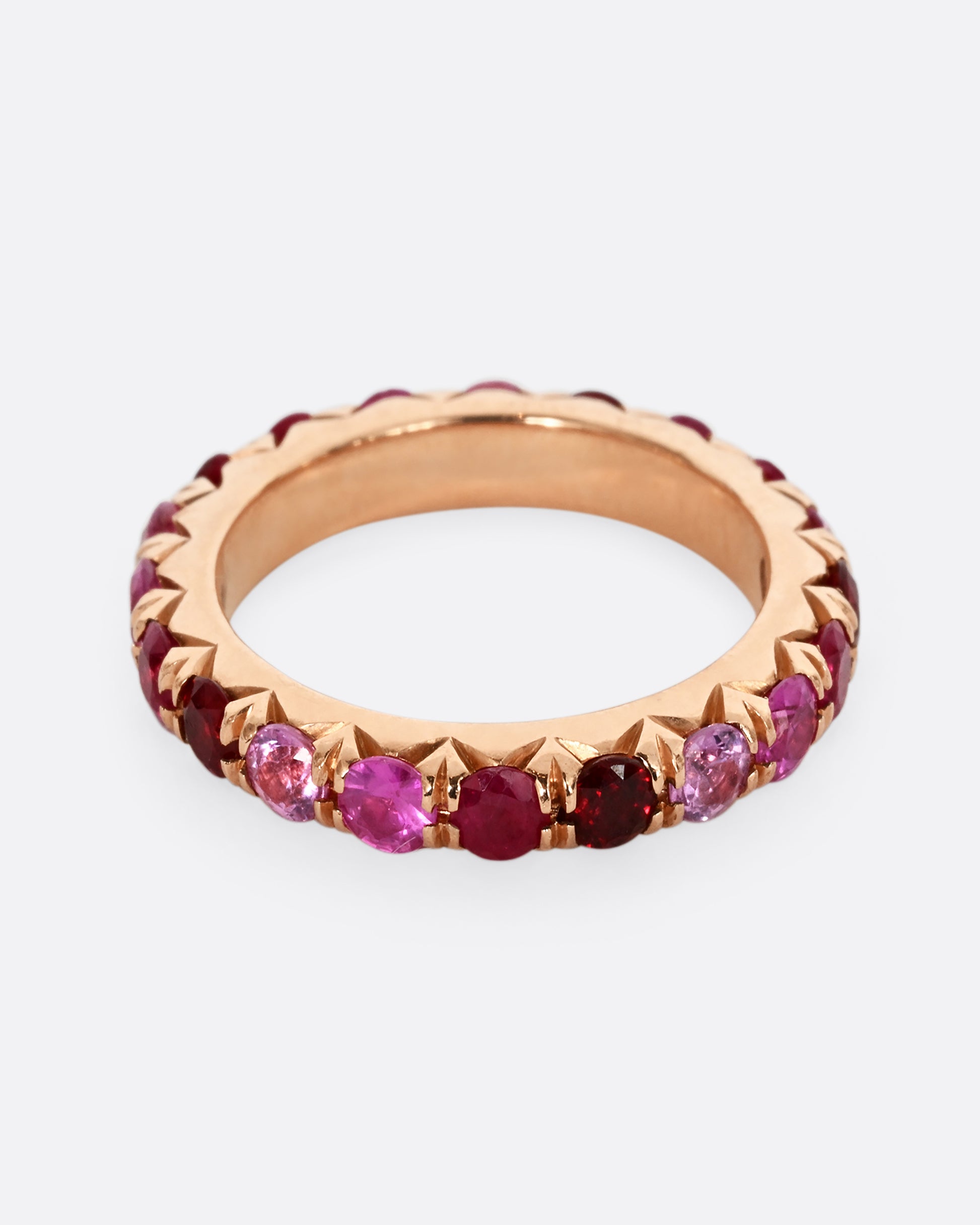 A rose gold eternity band with pink and red cut rubies.