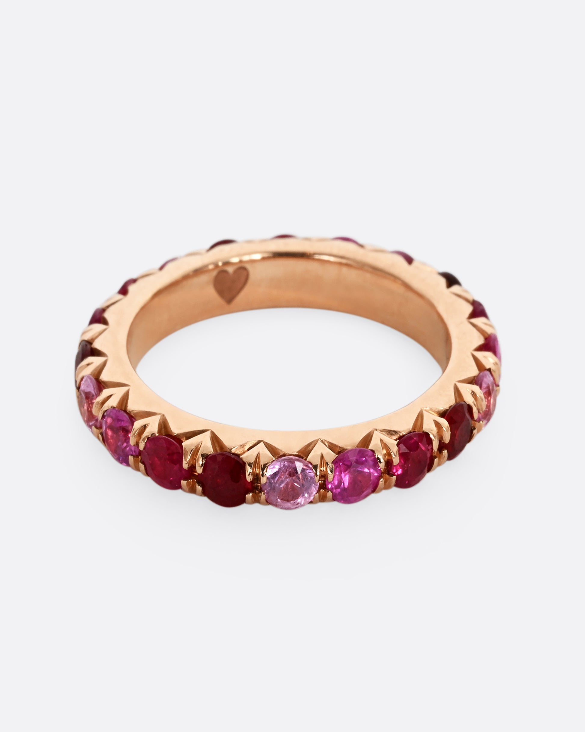 A rose gold eternity band with pink and red cut rubies.