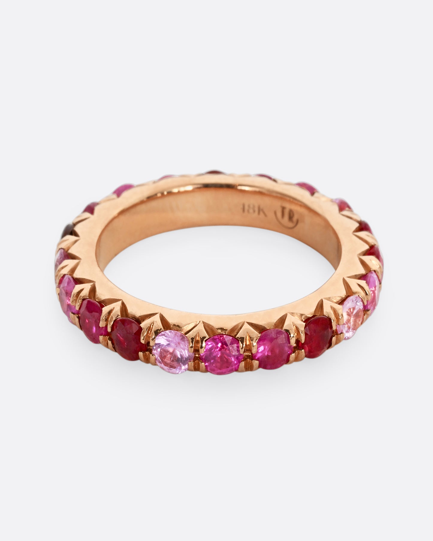 A rose gold eternity band with pink and red cut rubies.