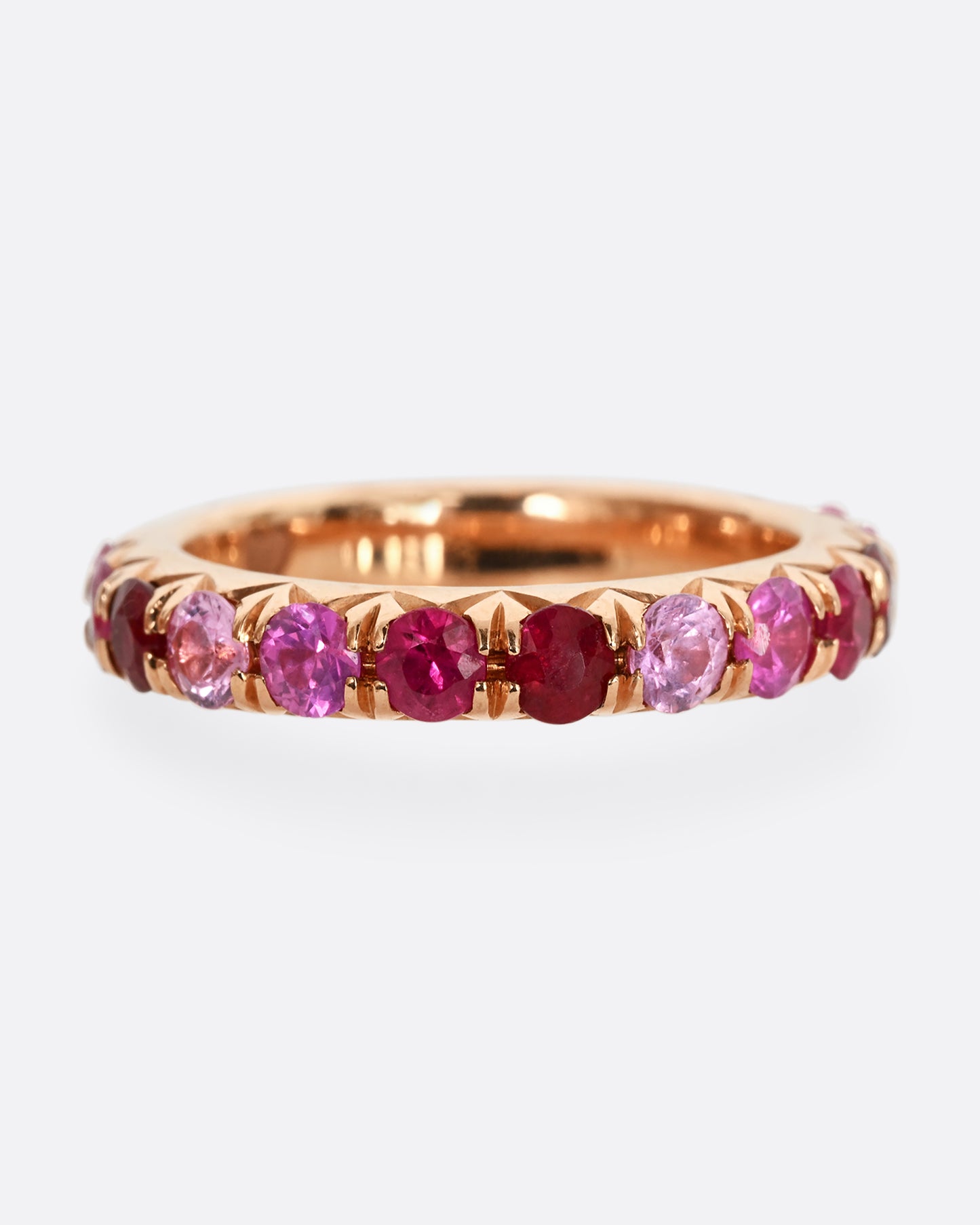 A rose gold eternity band with pink and red cut rubies.