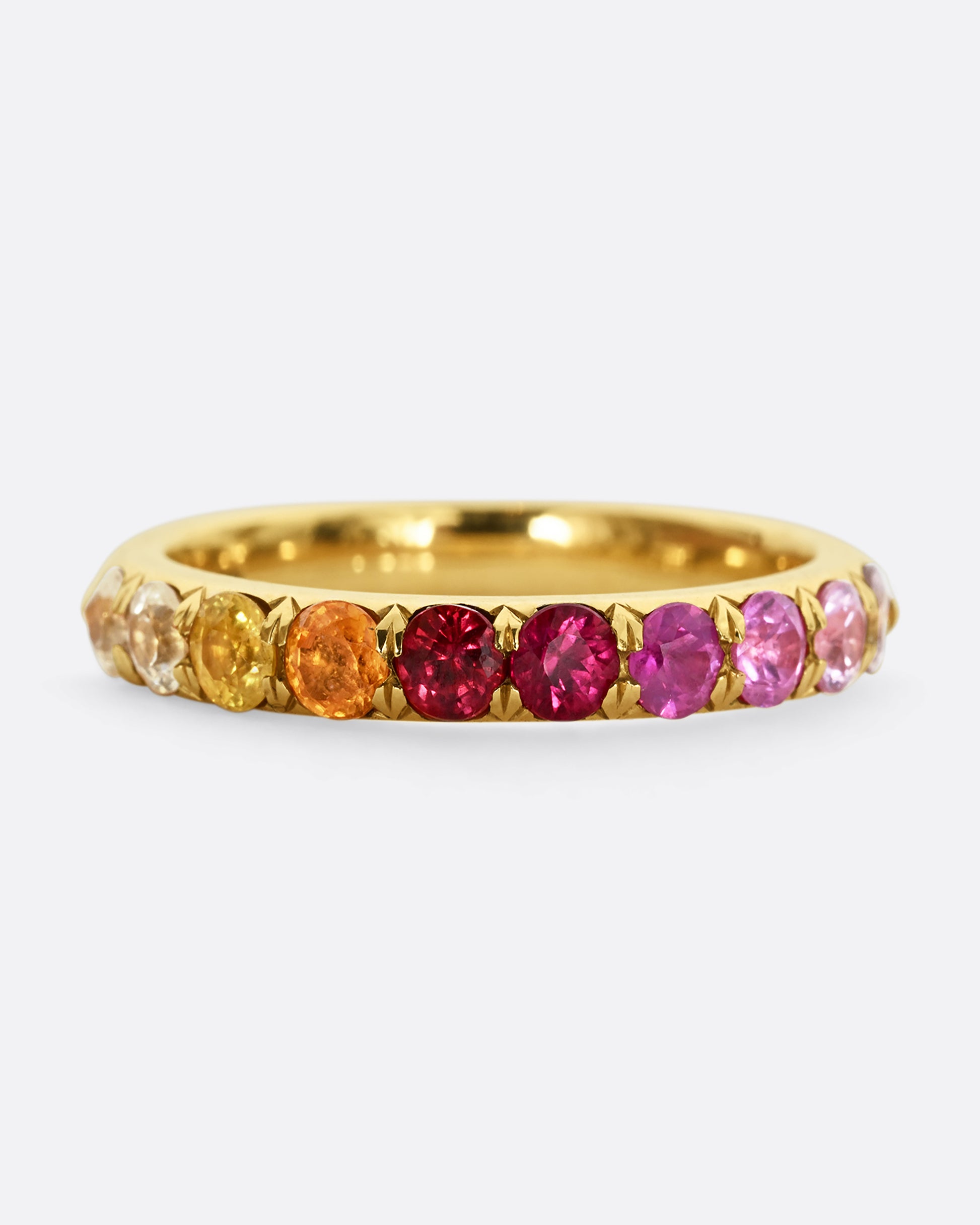 A yellow gold half eternity band with gradient orange red and pink cut sapphires. Shown from the front.