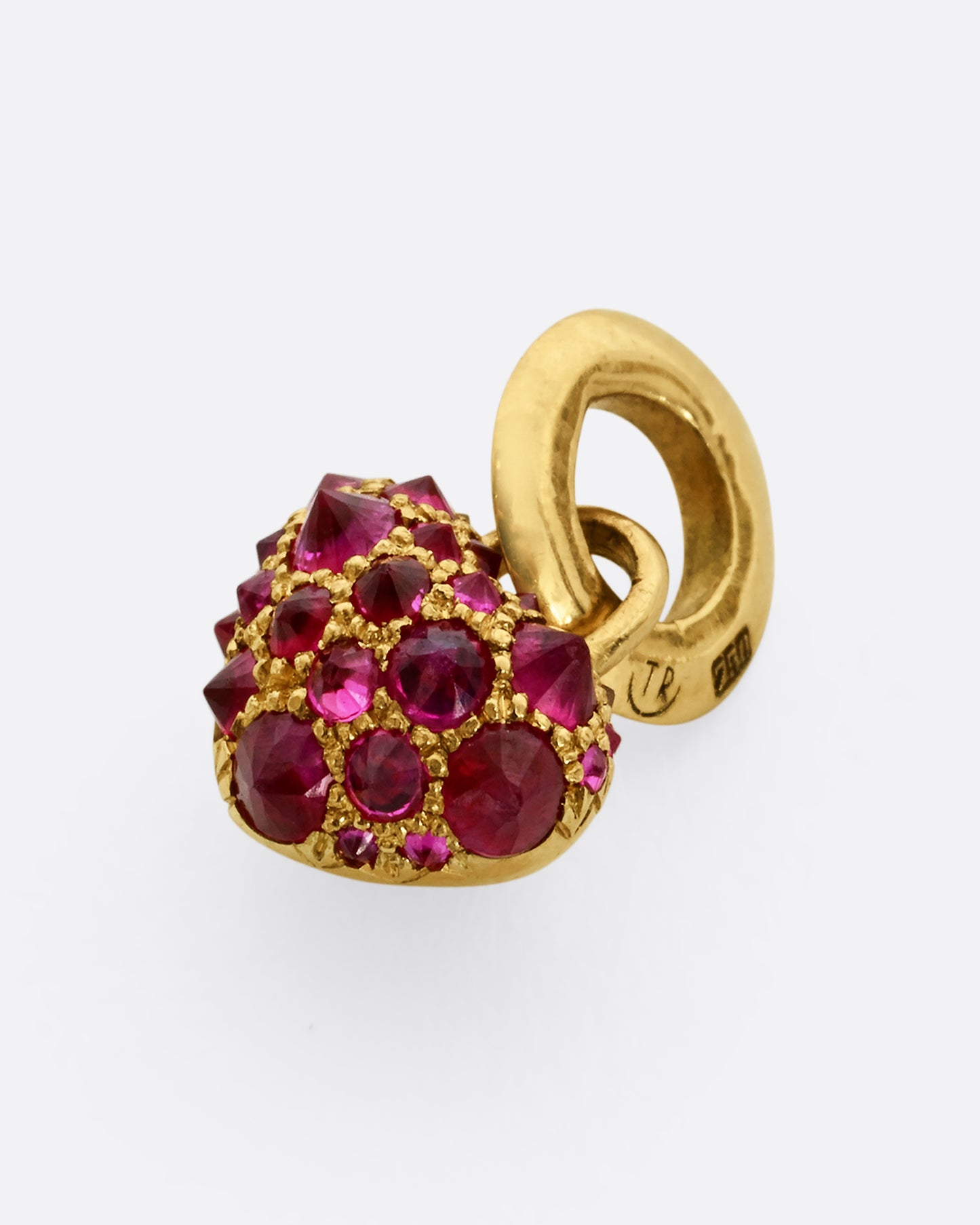 A yellow gold heart shaped charm with inverted rubies throughout. View laying flat.