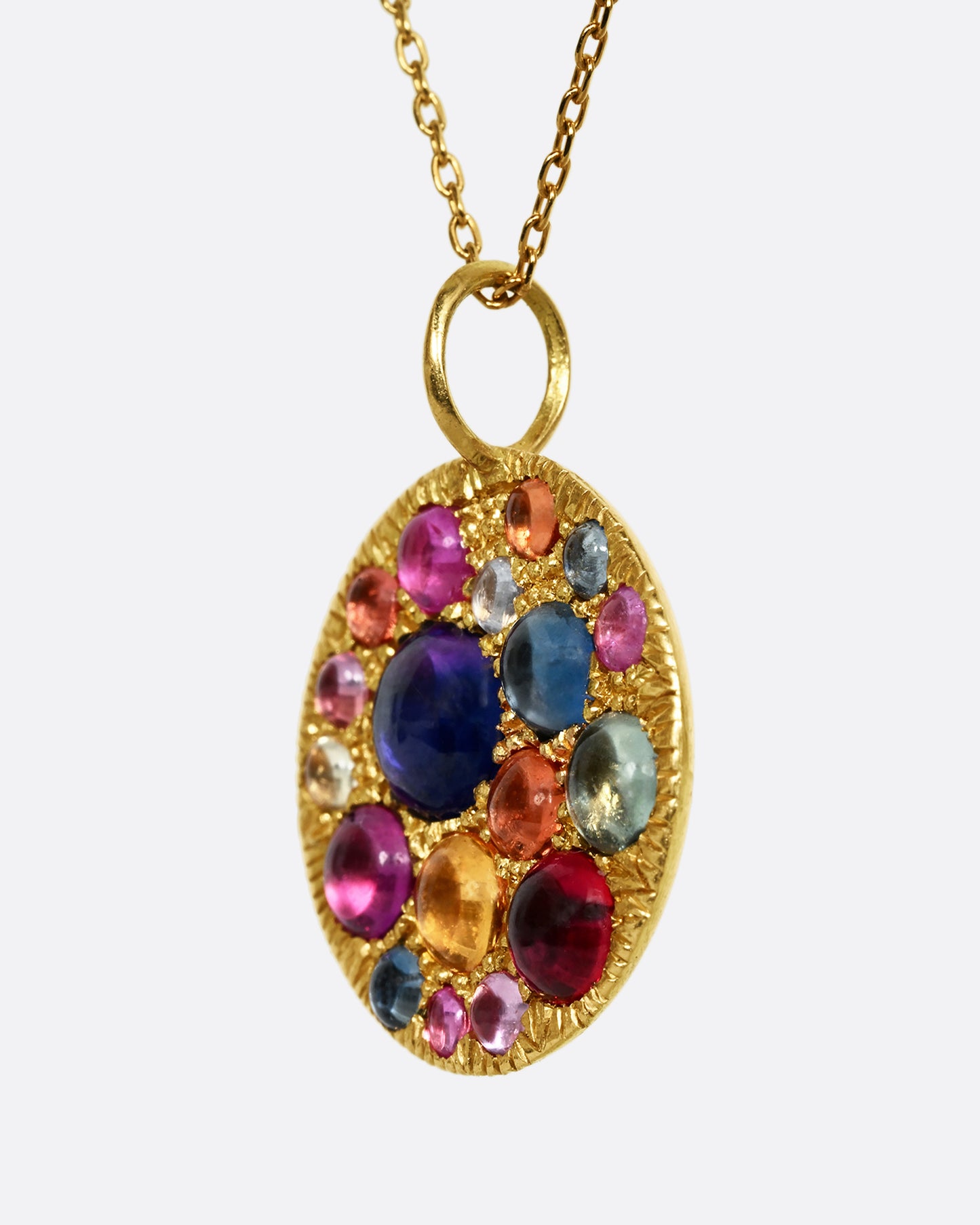 A yellow gold pendant with multicolor cabochon sapphires. Shown from the side.