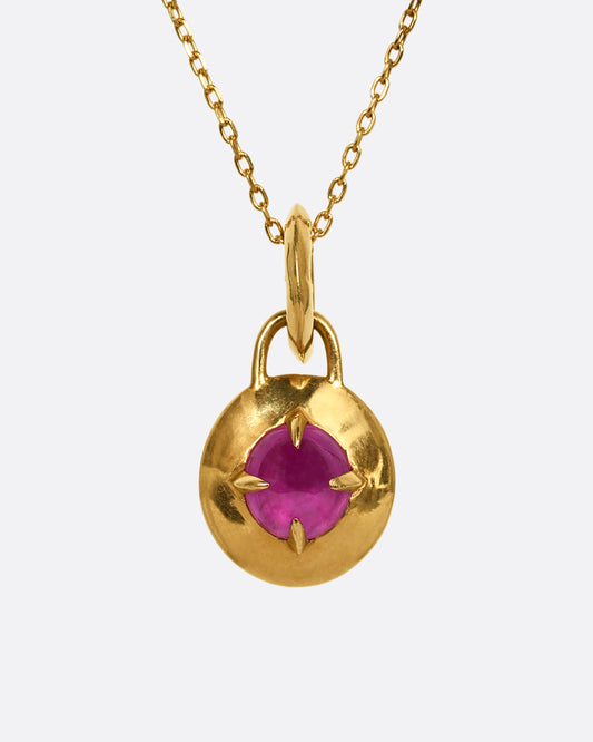 A ruby set in a yellow gold lock shaped pendant. Shown from the front.