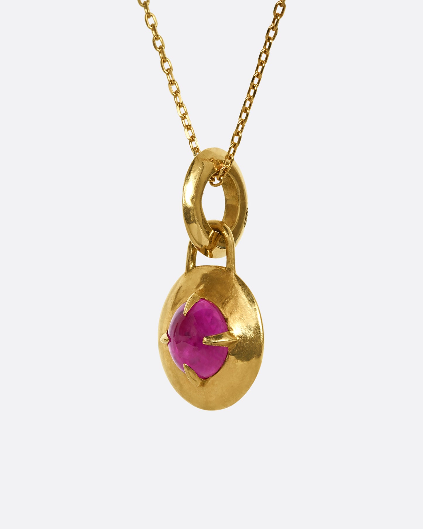 A ruby set in a yellow gold lock shaped pendant. Shown from the side.