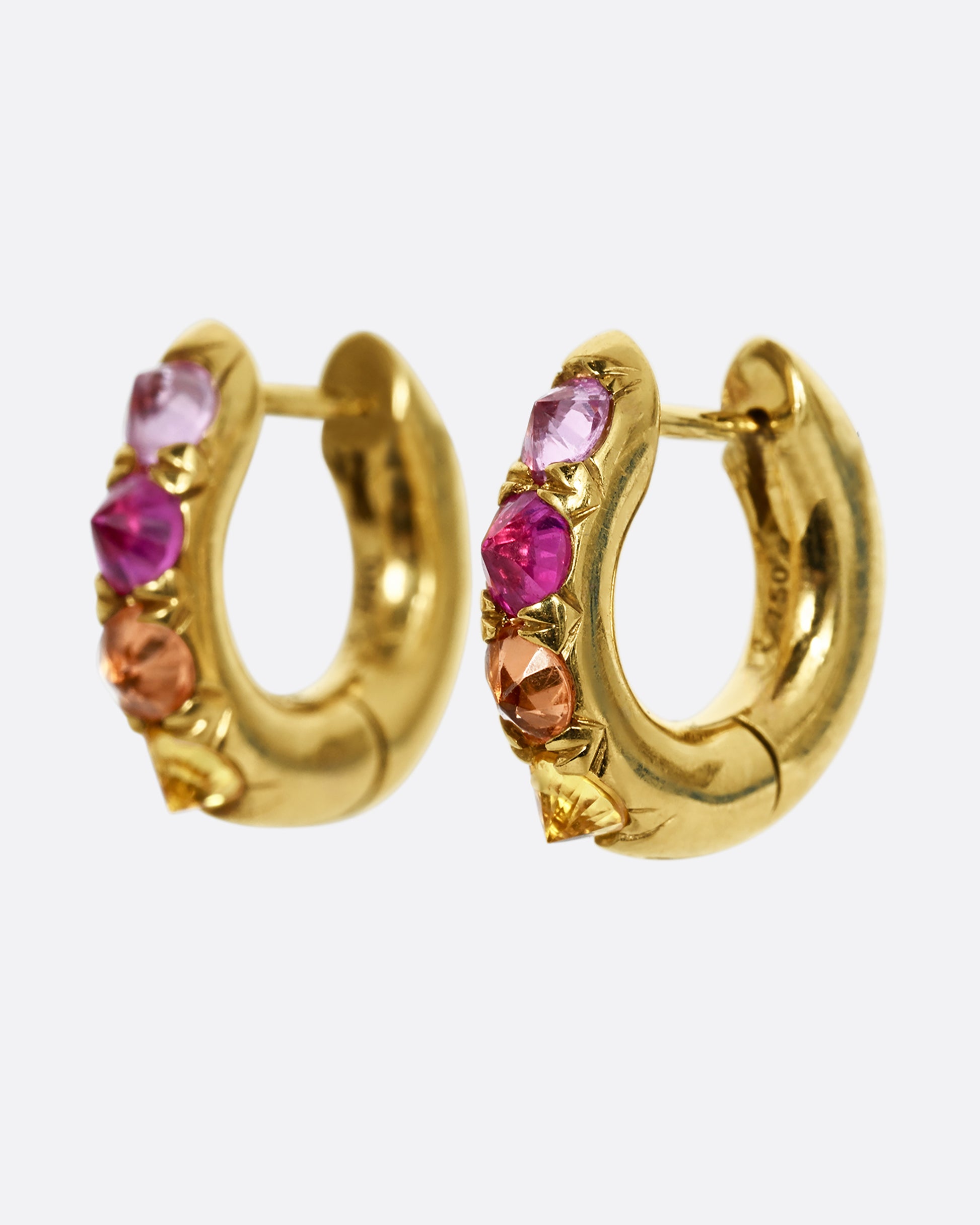 Gradient pink and orange inverted sapphires set in 18k yellow gold huggie hoops. Shown from the side.