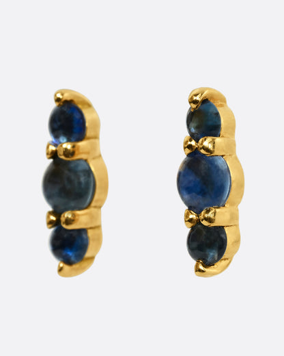 Stud earrings made of three blue sapphire cabochons set in yellow gold. Shown from the side.