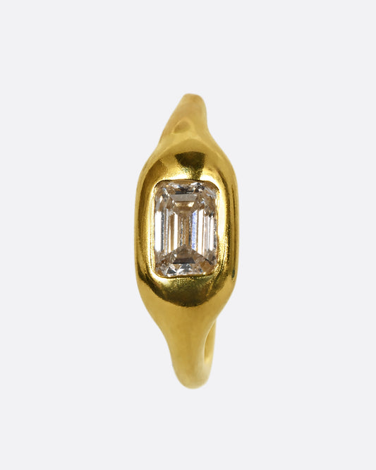 A yellow gold hoop with a single baguette diamond. Shown from the front.