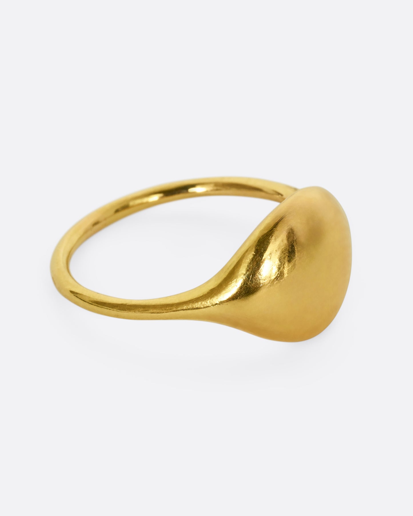 A yellow gold rounded signet ring. Shown from the side.