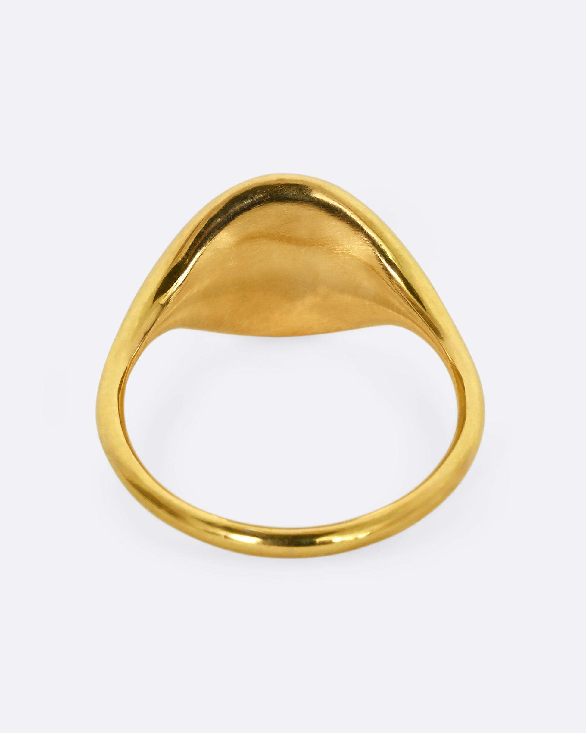 A yellow gold rounded signet ring. Shown from the back.