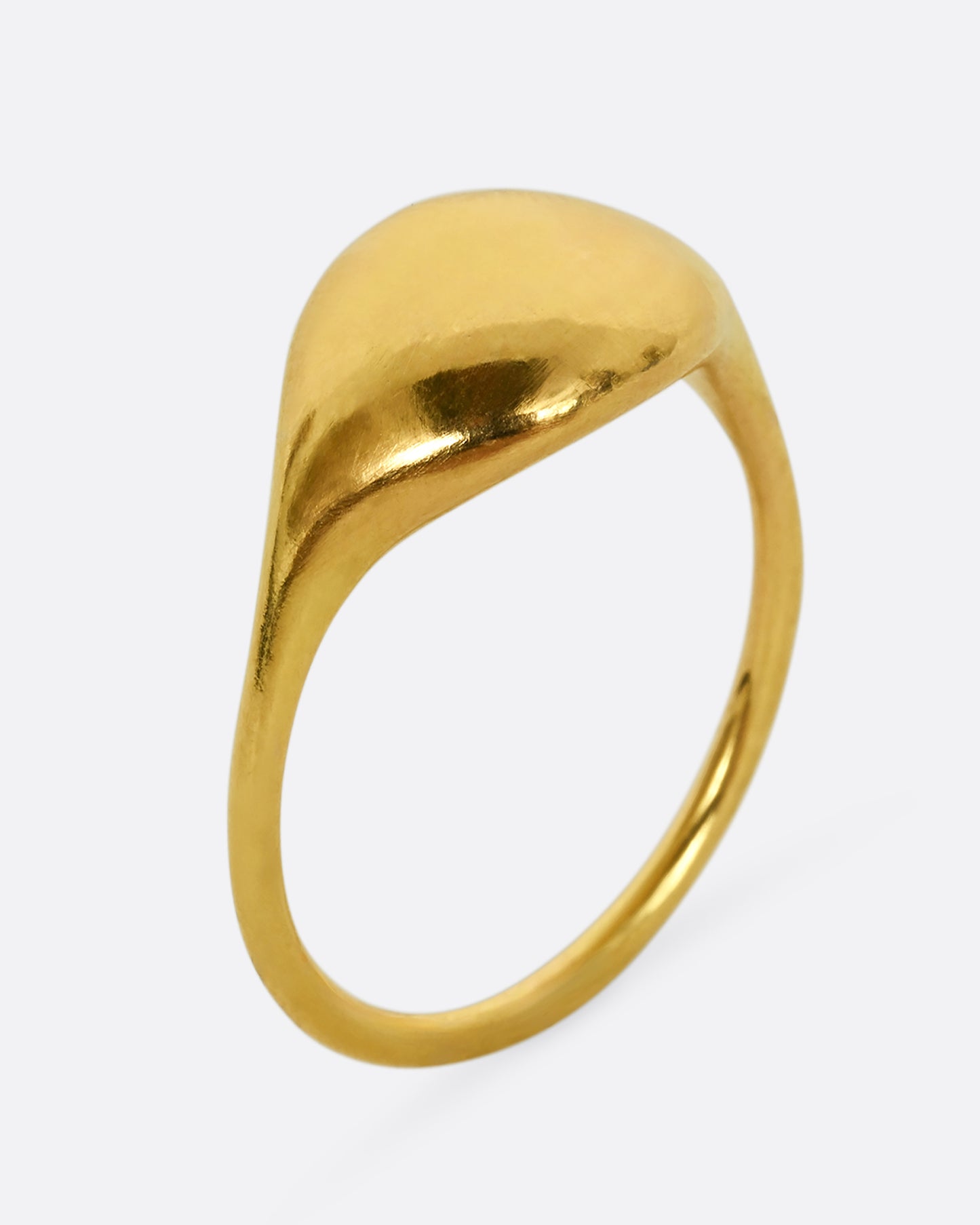 A yellow gold rounded signet ring. Shown standing from the side.