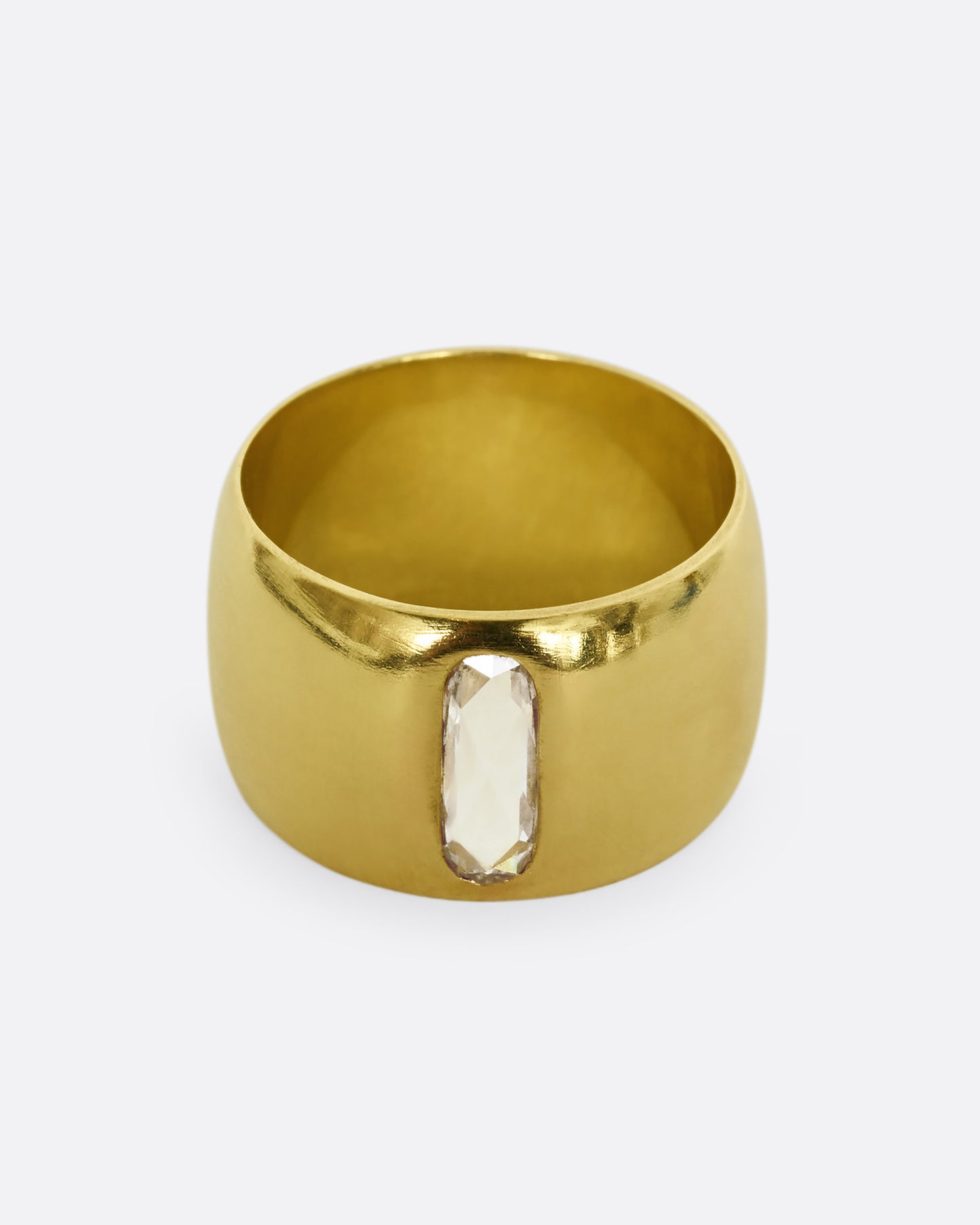 A yellow gold cigar band with an oval shaped diamond. Shown from the front.