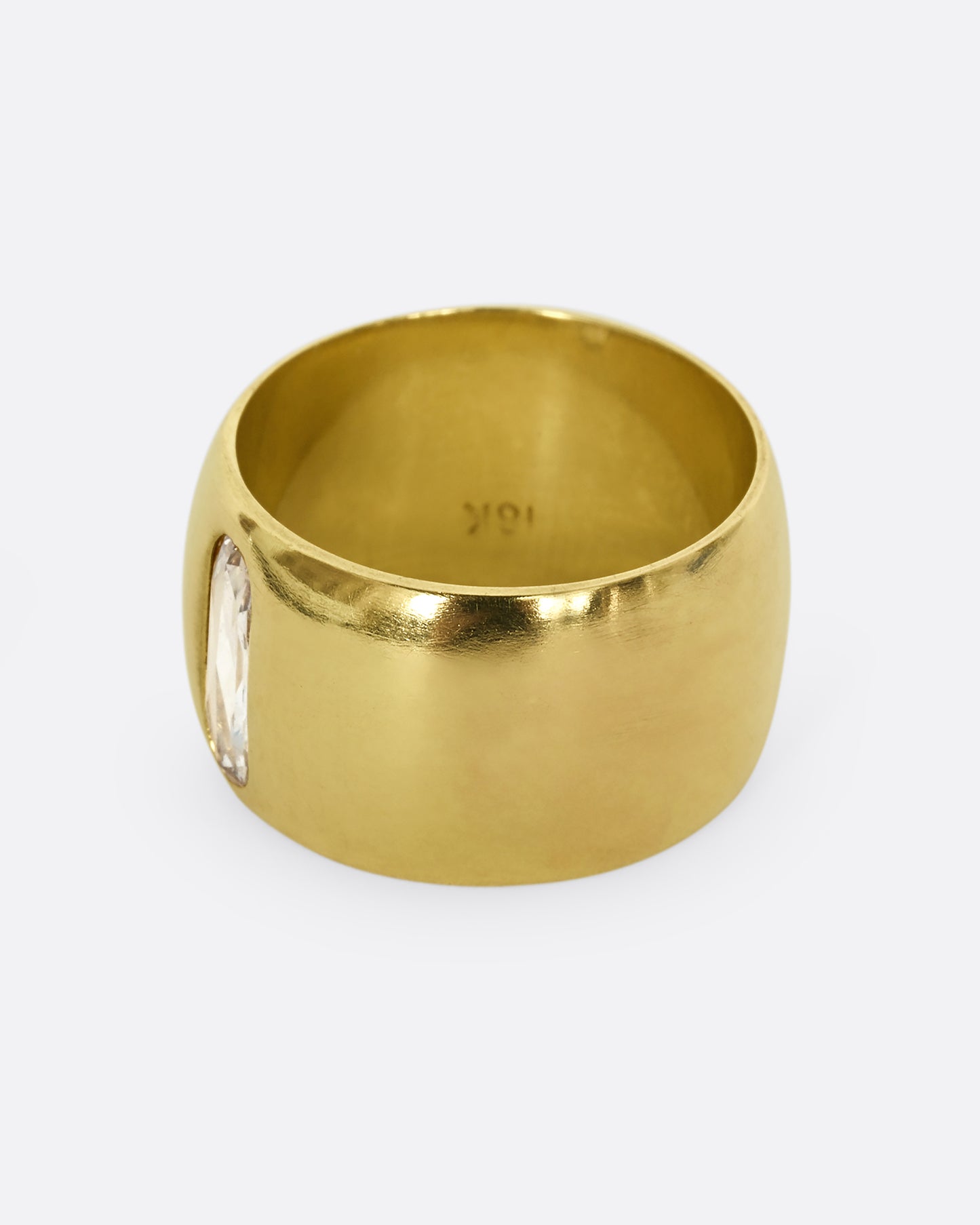 A yellow gold cigar band with an oval shaped diamond. Shown from the back.