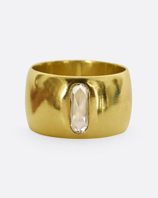 A yellow gold cigar band with an oval shaped diamond. Shown from the front.