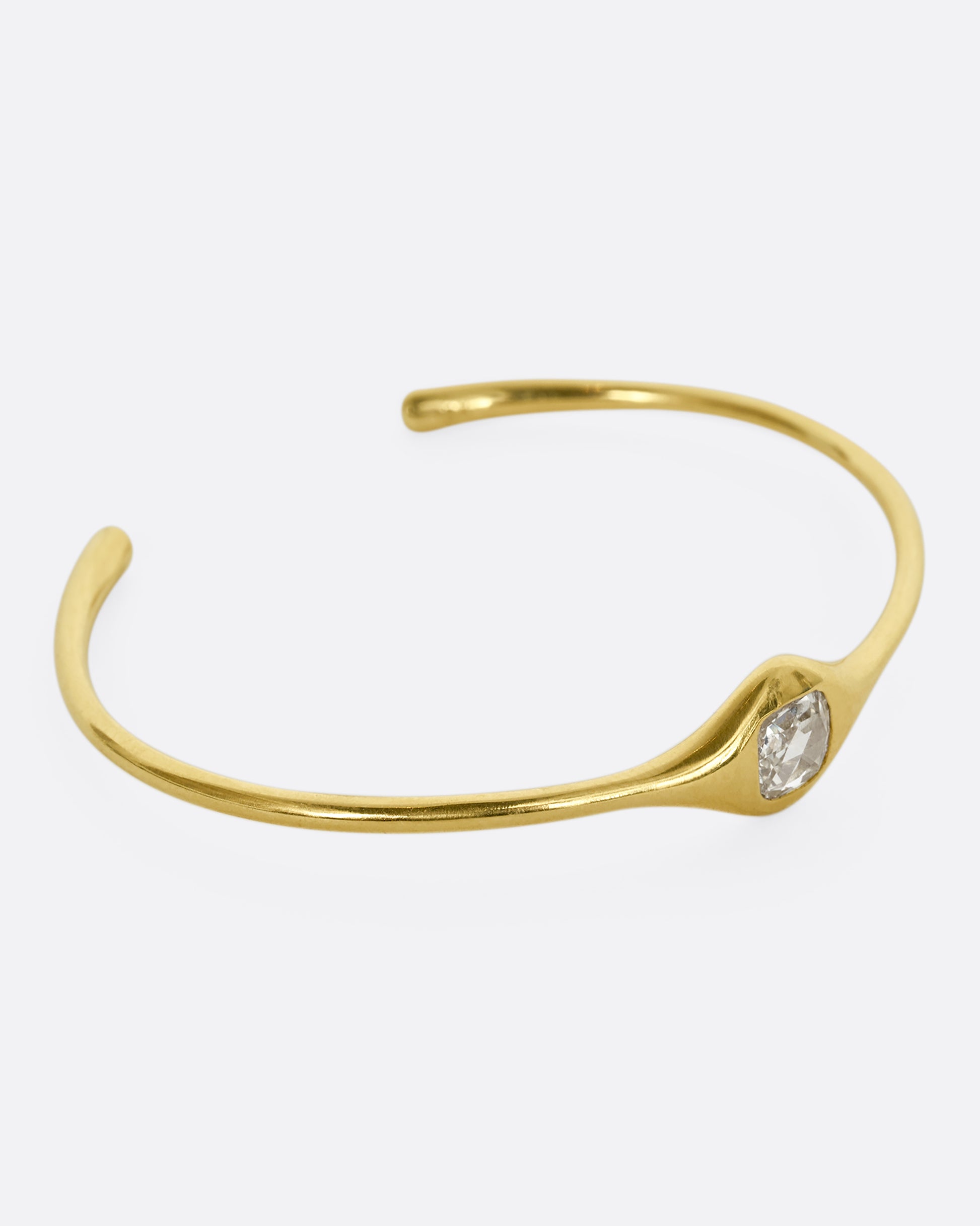 A yellow gold cuff bracelet with a rose cut cushion shaped diamond. Shown from the side.