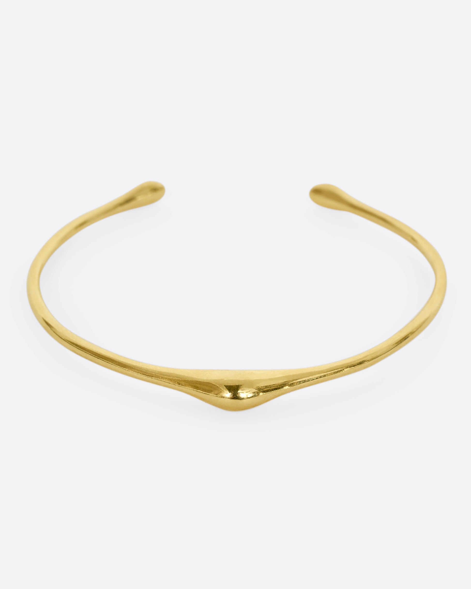 A yellow gold cuff bracelet with a bump. Shown from the front.