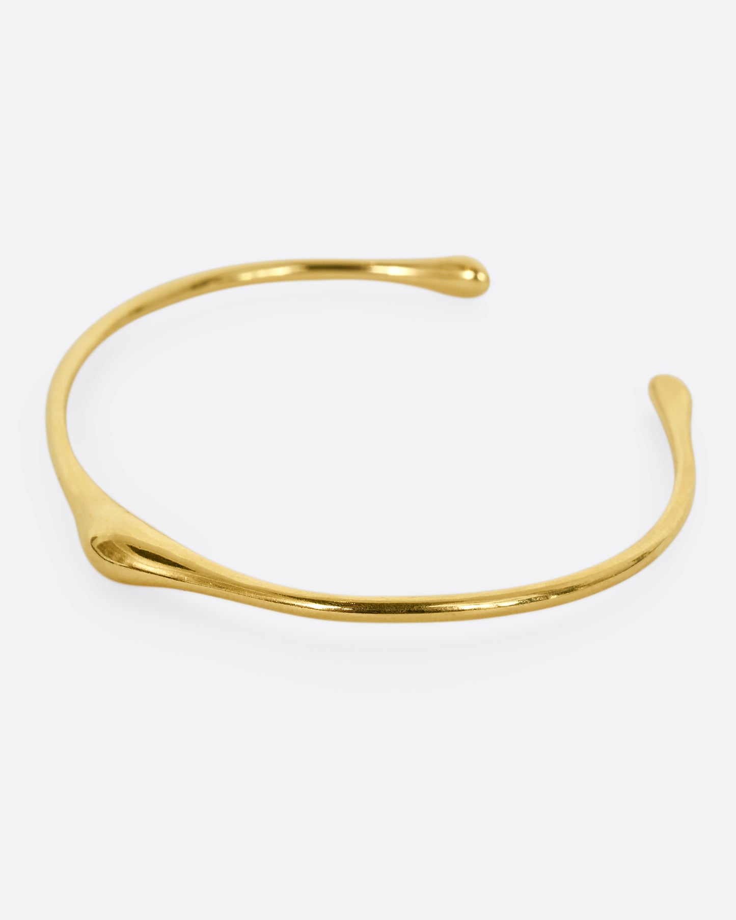 A yellow gold cuff bracelet with a bump. Shown from the side.