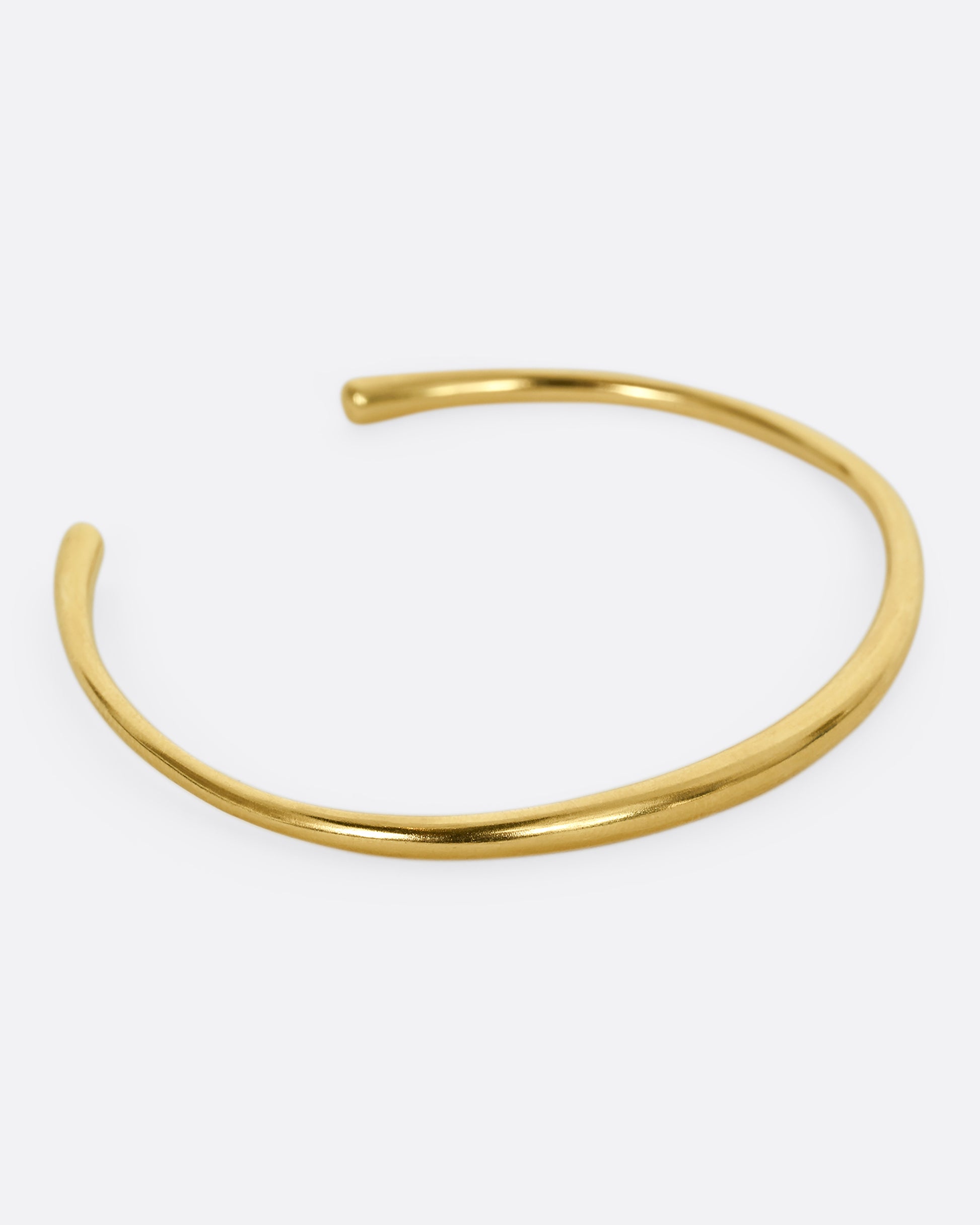 A yellow gold cuff bracelet. Shown from the side.