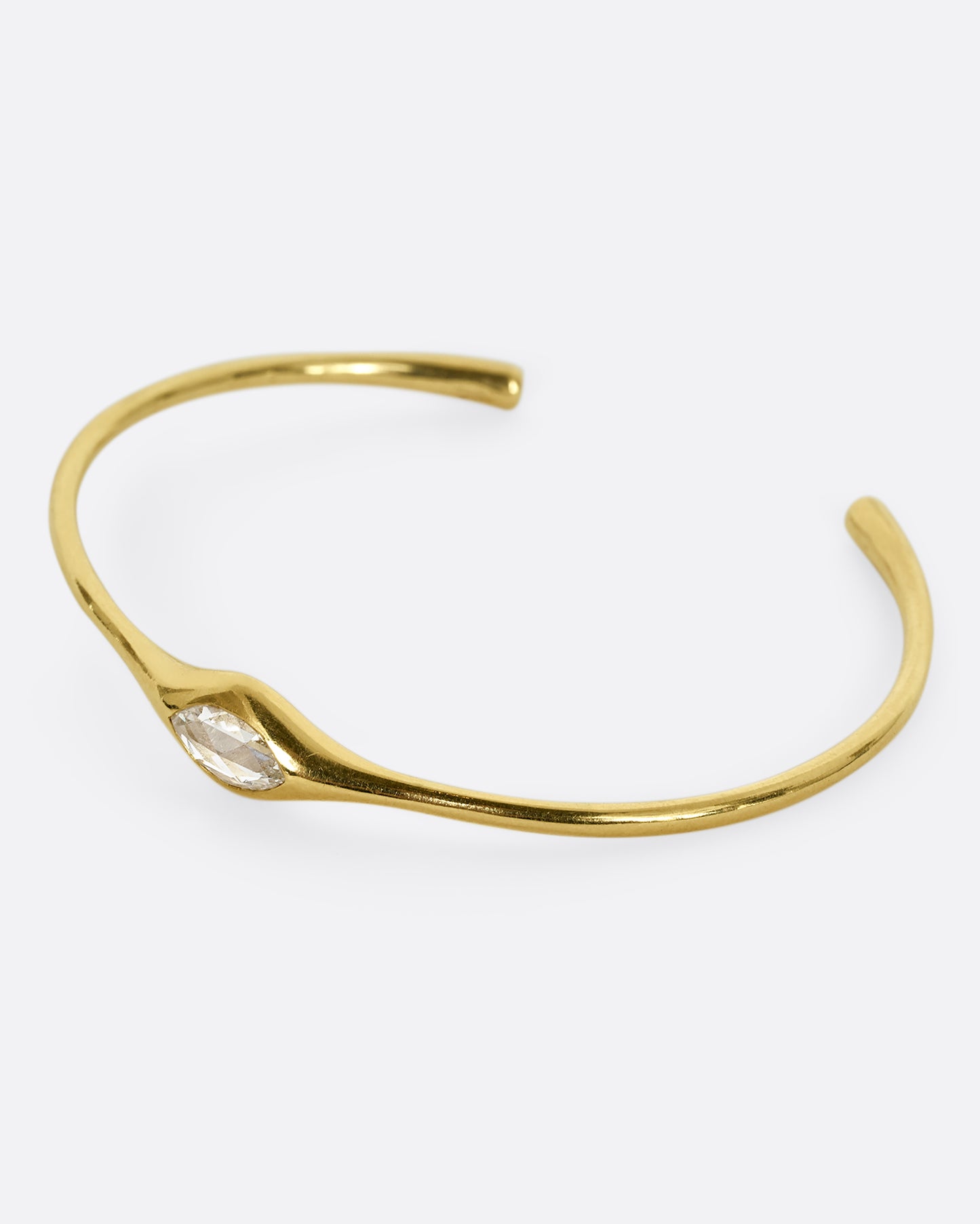 A yellow gold cuff with a marquis diamond. Shown from the side.