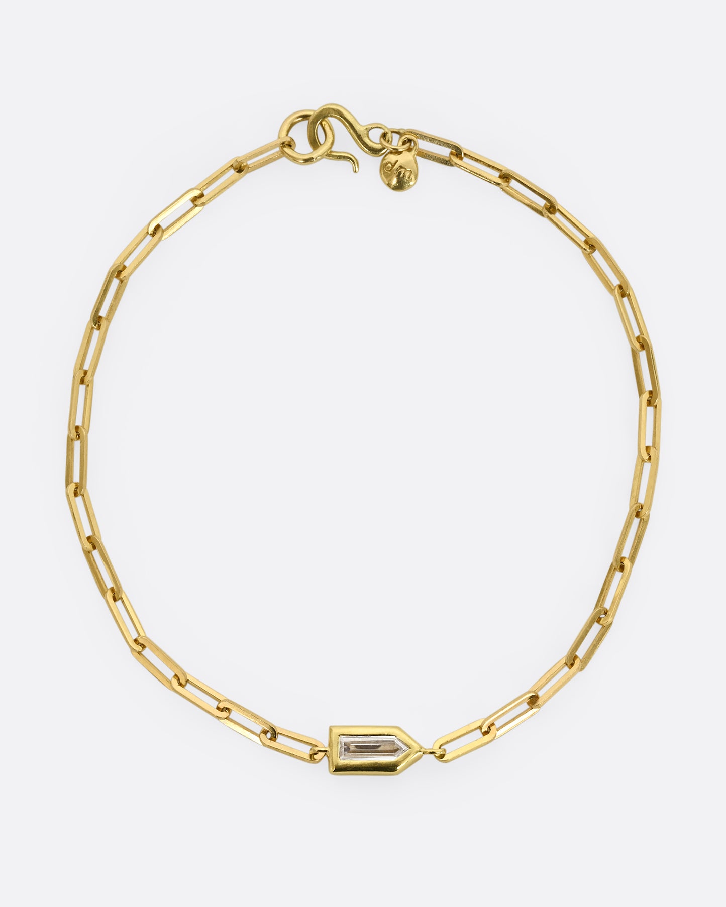 A yellow gold paperclip chain bracelet with a bullet shaped diamond channel. Shown closed, from above.