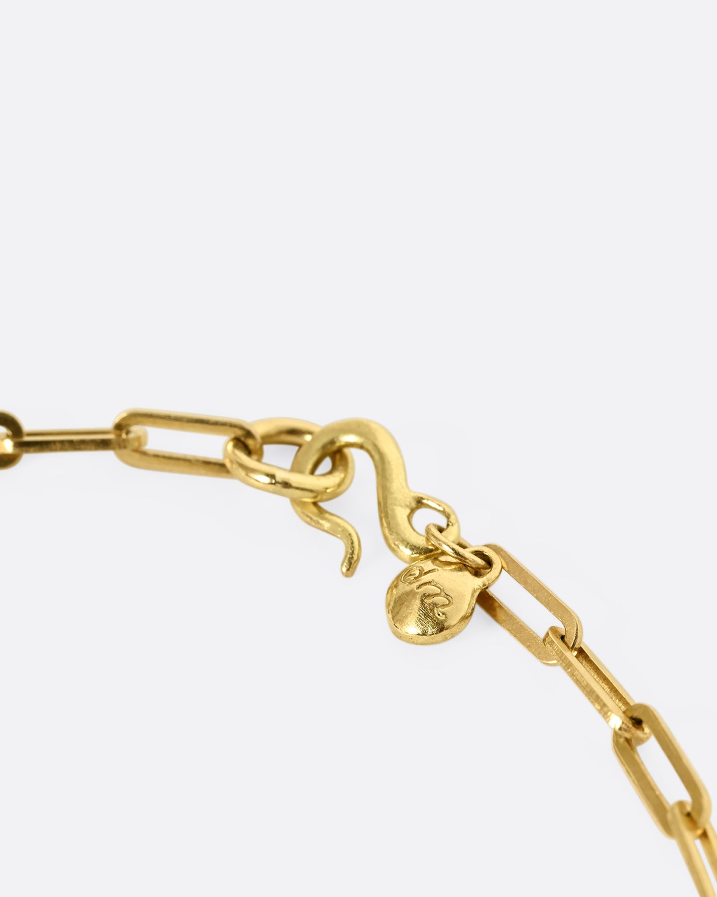 A yellow gold paperclip chain bracelet with a bullet shaped diamond channel. Close up of the clasp.