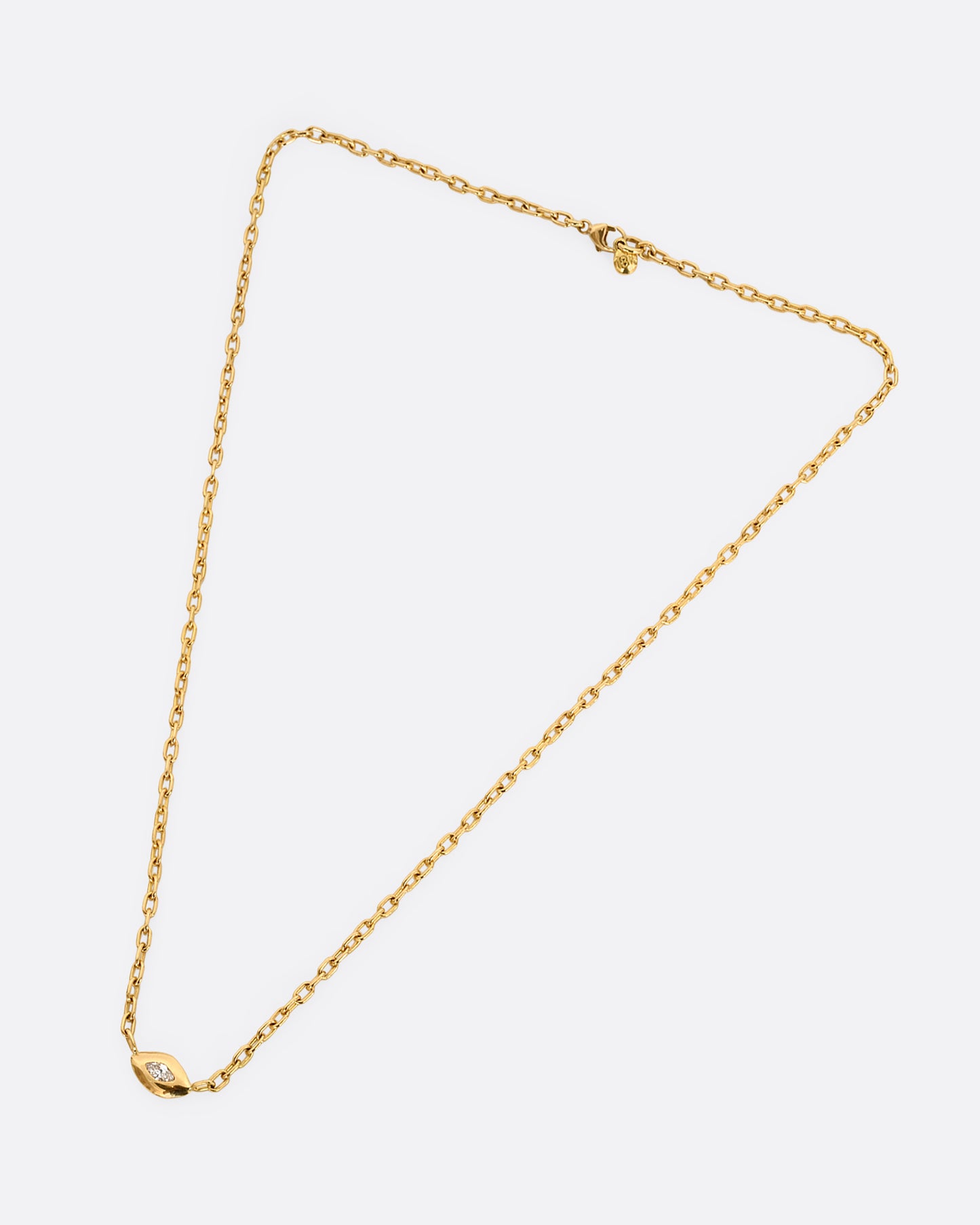 A yellow gold necklace with a marquis diamond pendant. Shown laying flat.