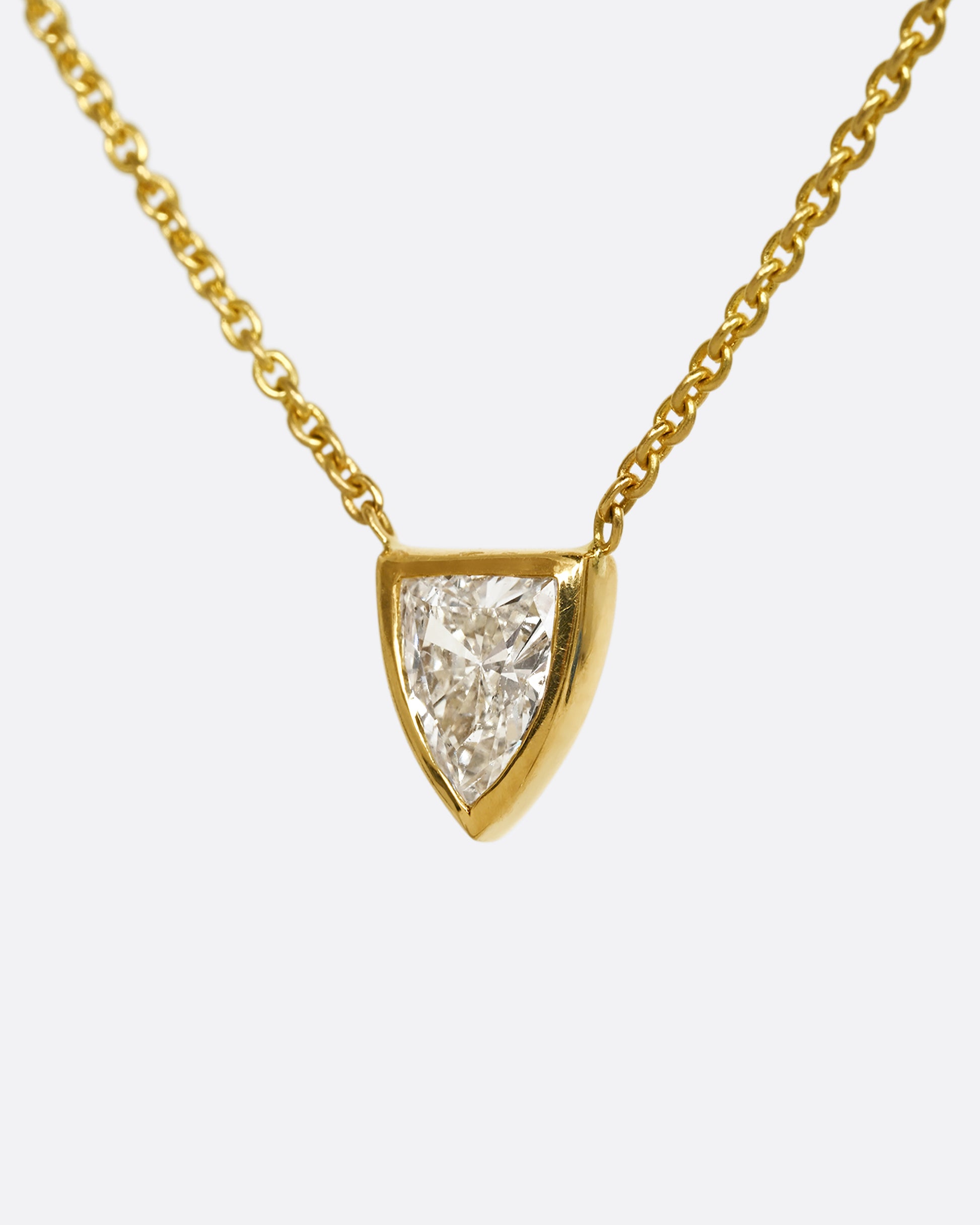 A yellow gold necklace with a shield shaped diamond. Shown from the side.