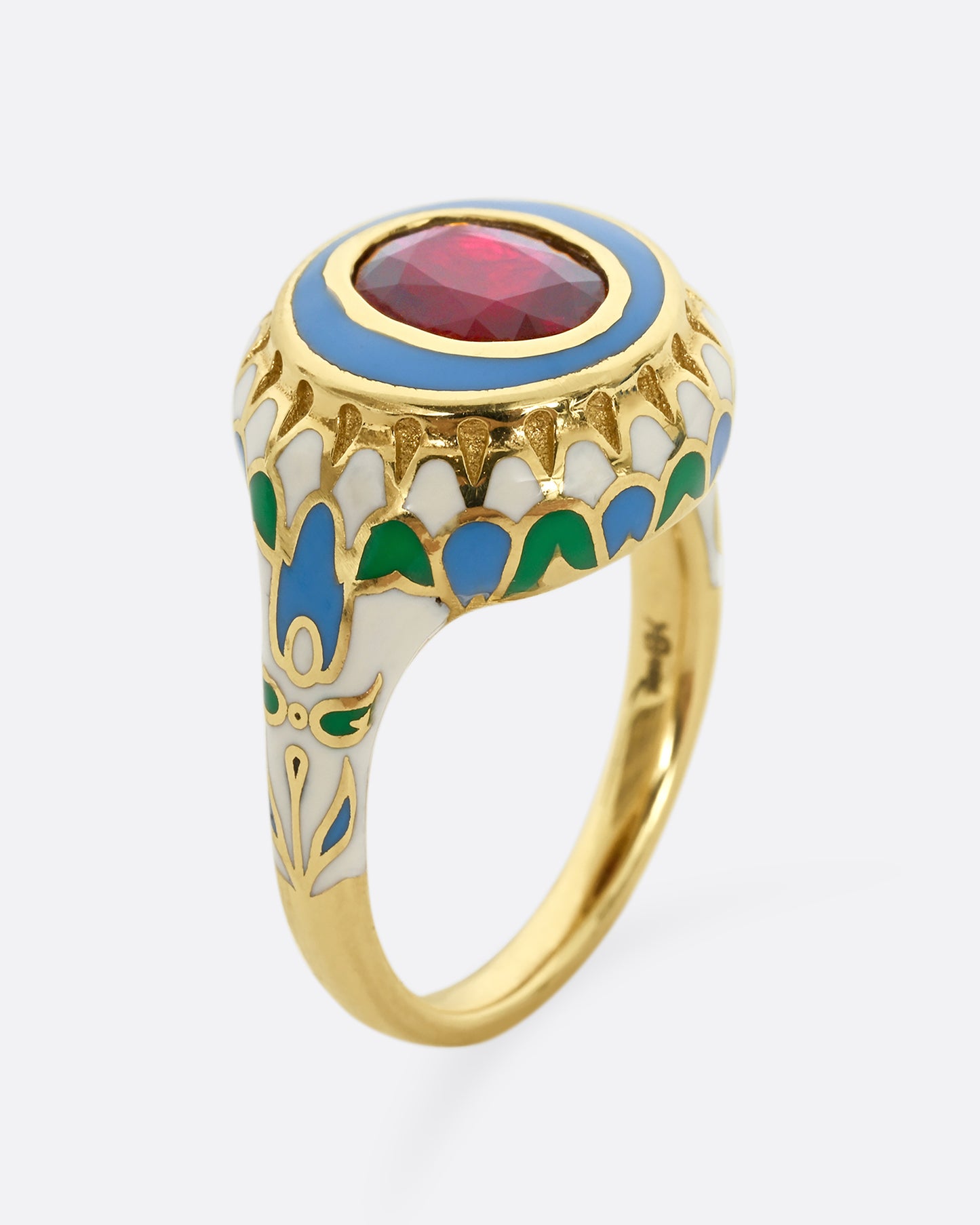 A yellow gold ring with multicolor enamel around an oval shaped ruby. Shown from the side, standing up.