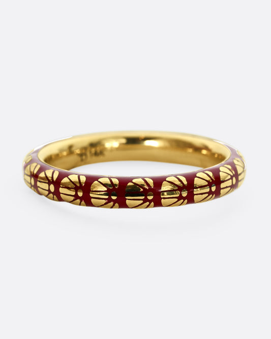 A yellow gold ring with burgundy enamel and a floral motif around the entire band.