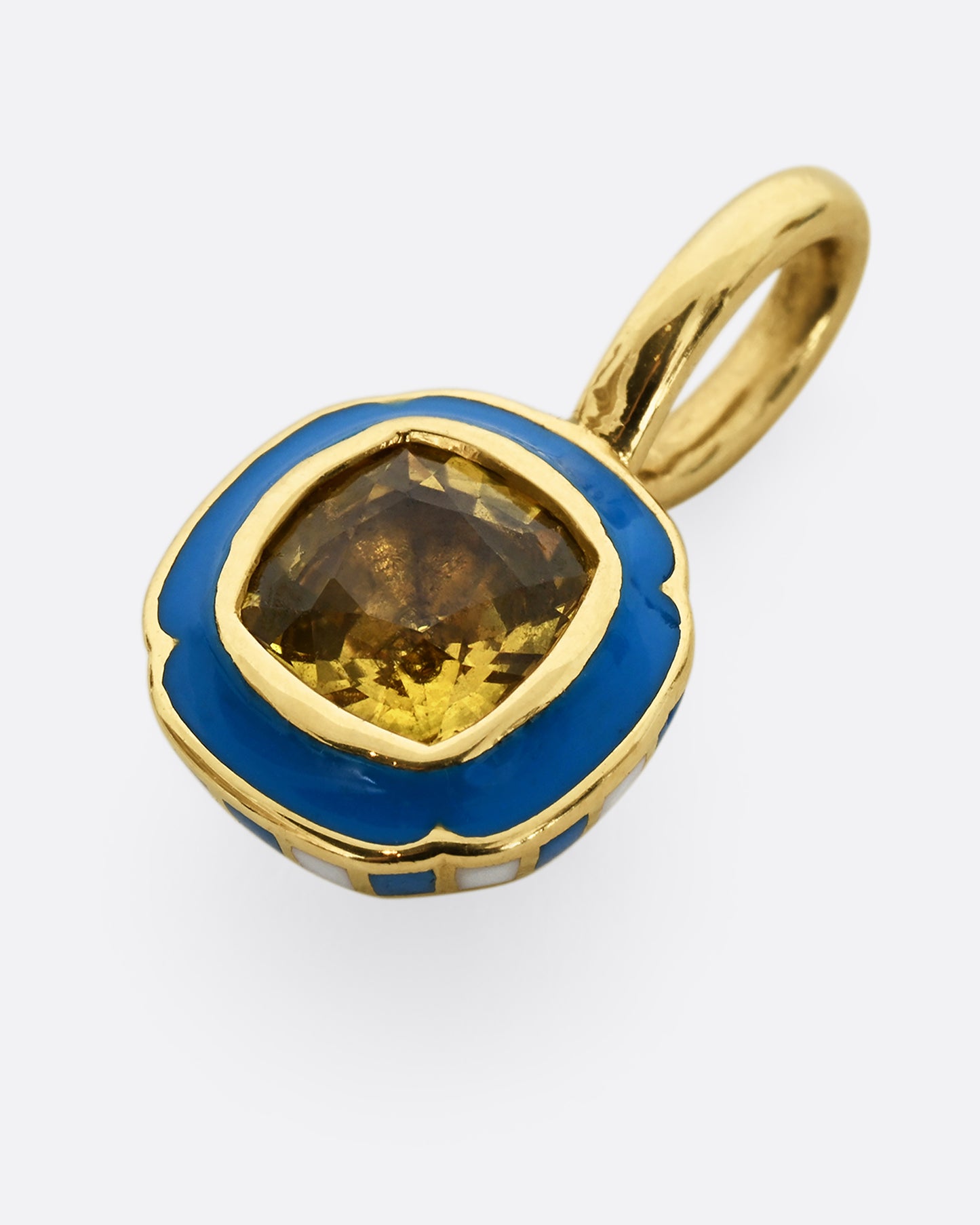 A yellow gold pendant with blue enamel surrounding a cushion cut yellow sapphire. Shown from the front, laying flat.