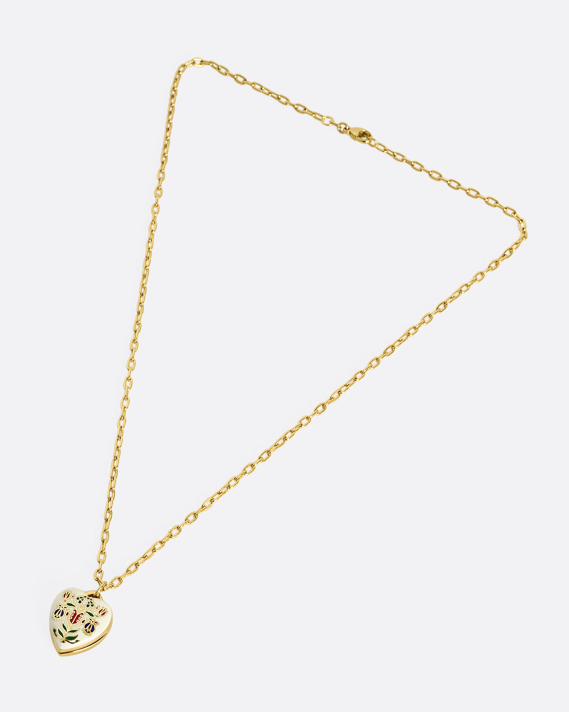 A yellow gold heart shaped locket with a multicolor floral motif on a heavy chain. Shown laying flat.